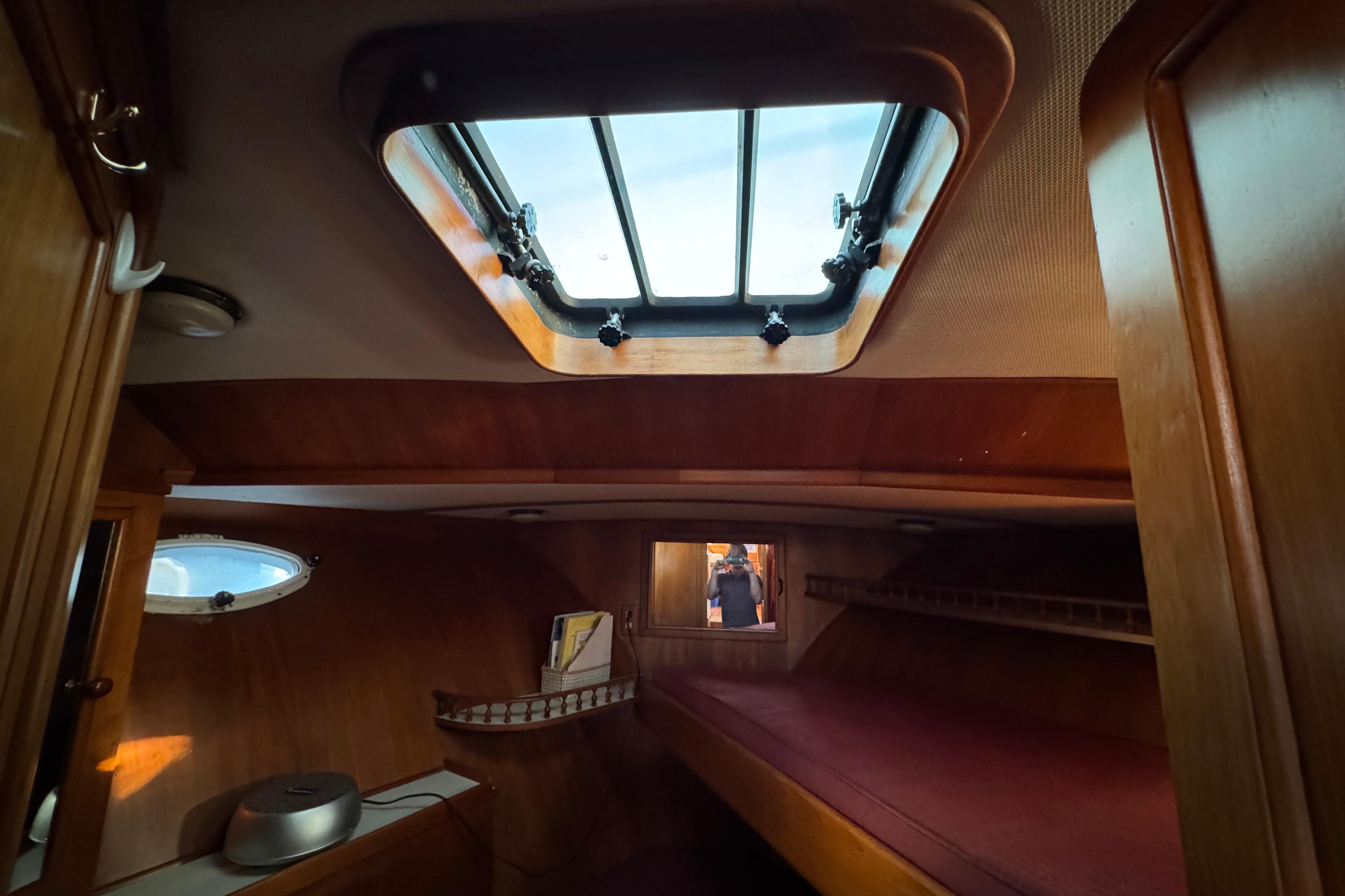 Cozy cabin interior of a 1987 President 37 yacht with wooden furnishings and skylight.