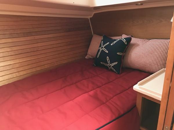 Cozy cabin interior of 2026 Back Cove 372 with red bedding and starfish-themed pillows.