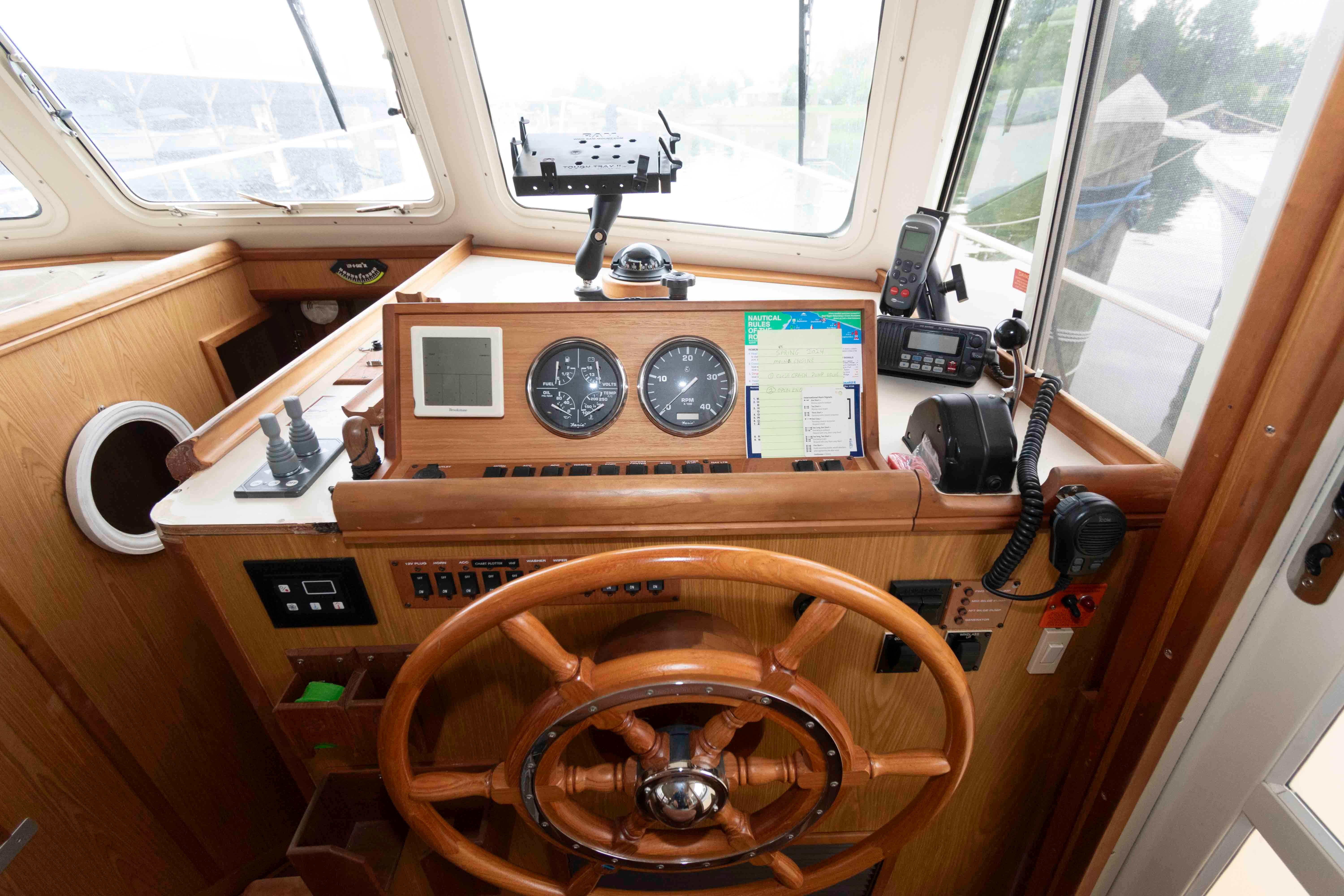 Helm of 2005 Mainship 400 Trawler with wooden wheel and navigation instruments.