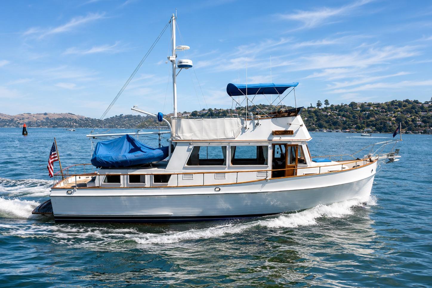 1989 Grand Banks 42 Classic yacht cruising on a sunny day, with scenic coastal backdrop.