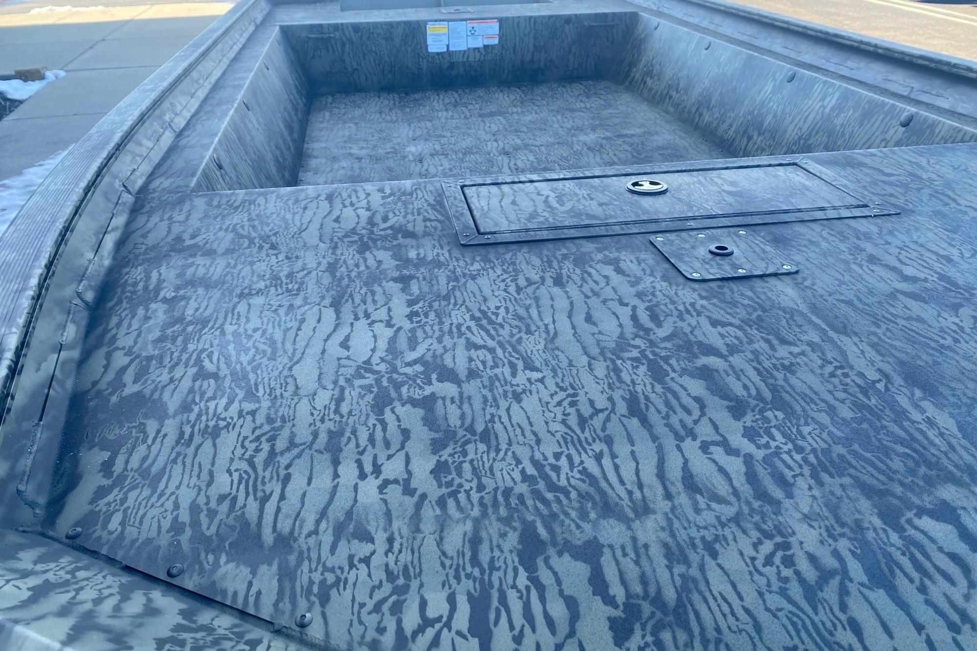 2026 Tracker Grizzly 1860 Utility boat interior with camouflage pattern and storage hatch.