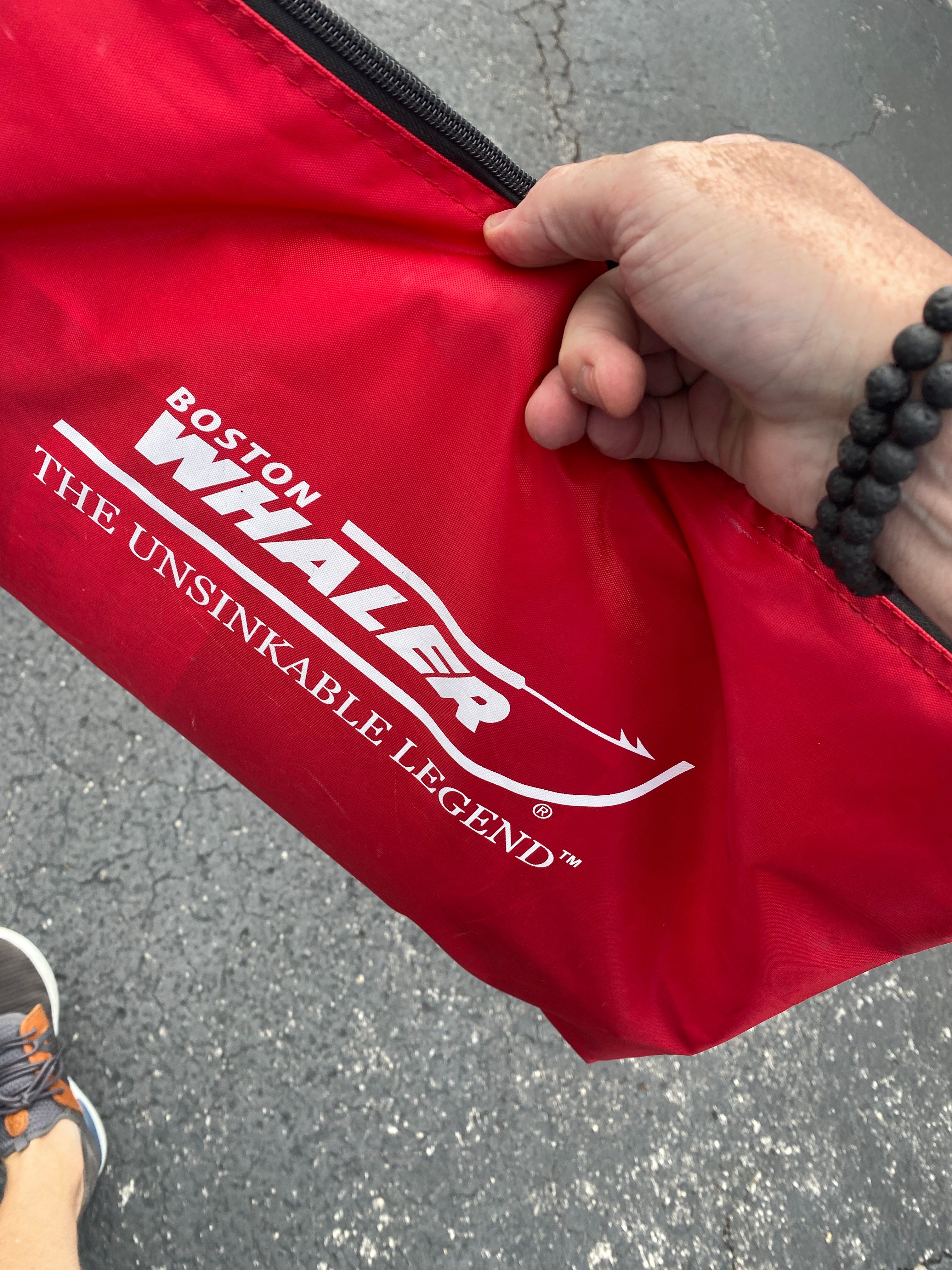 Red Boston Whaler bag with logo and slogan "The Unsinkable Legend."