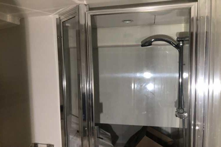 Shower area in 1997 Bayliner 3988 Motoryacht with glass enclosure and chrome fixtures.