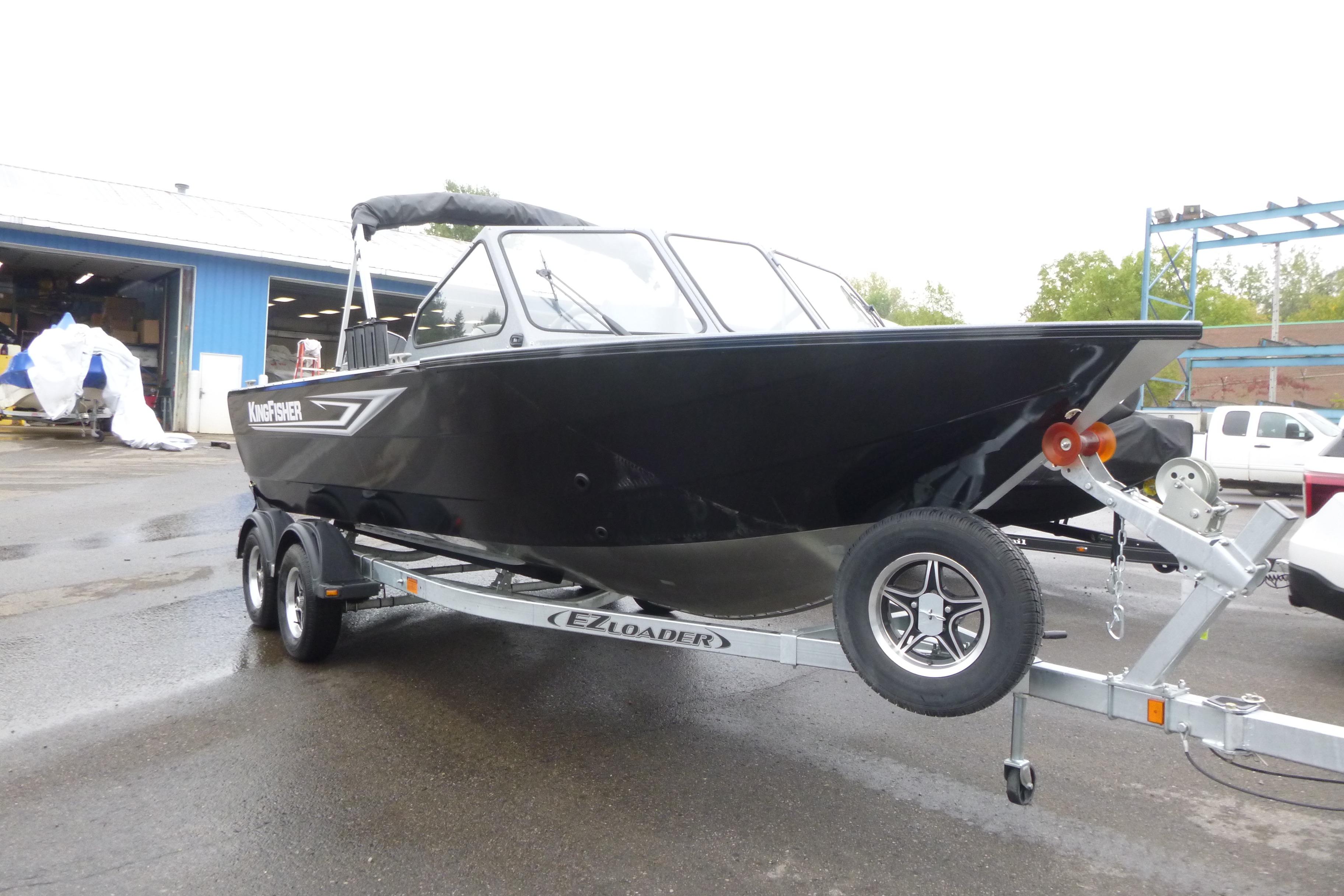 2026 KingFisher 2025 Escape boat on trailer, parked outdoors near a blue building.