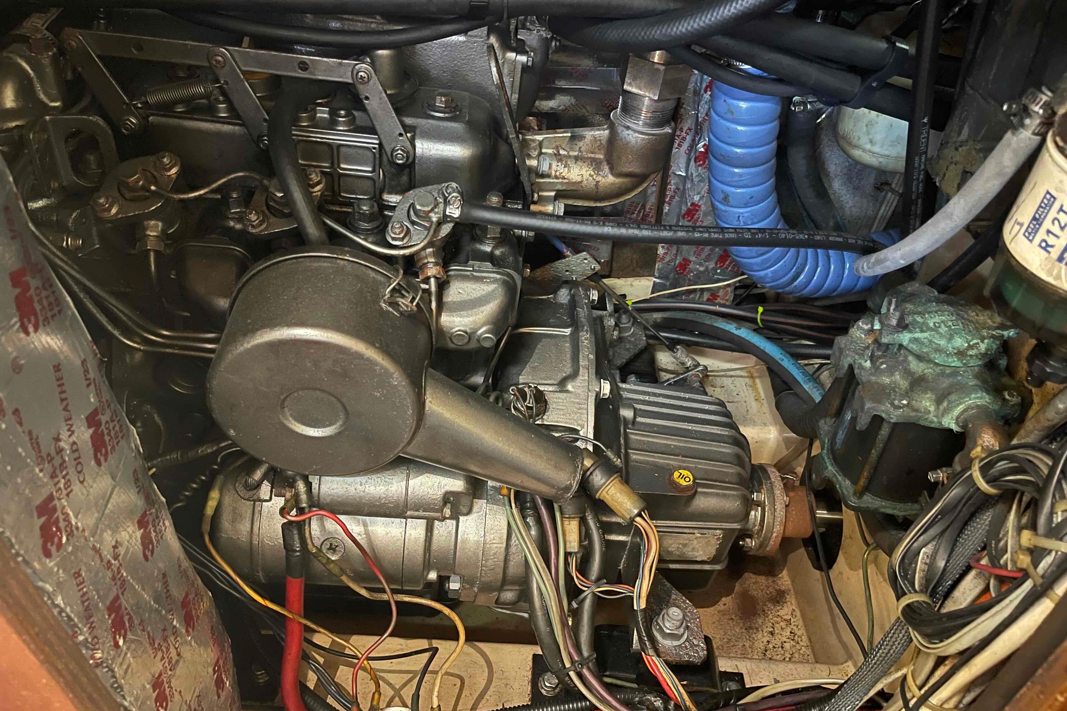 Engine compartment of a 1989 Island Packet 35 sailboat, showcasing mechanical components and wiring.