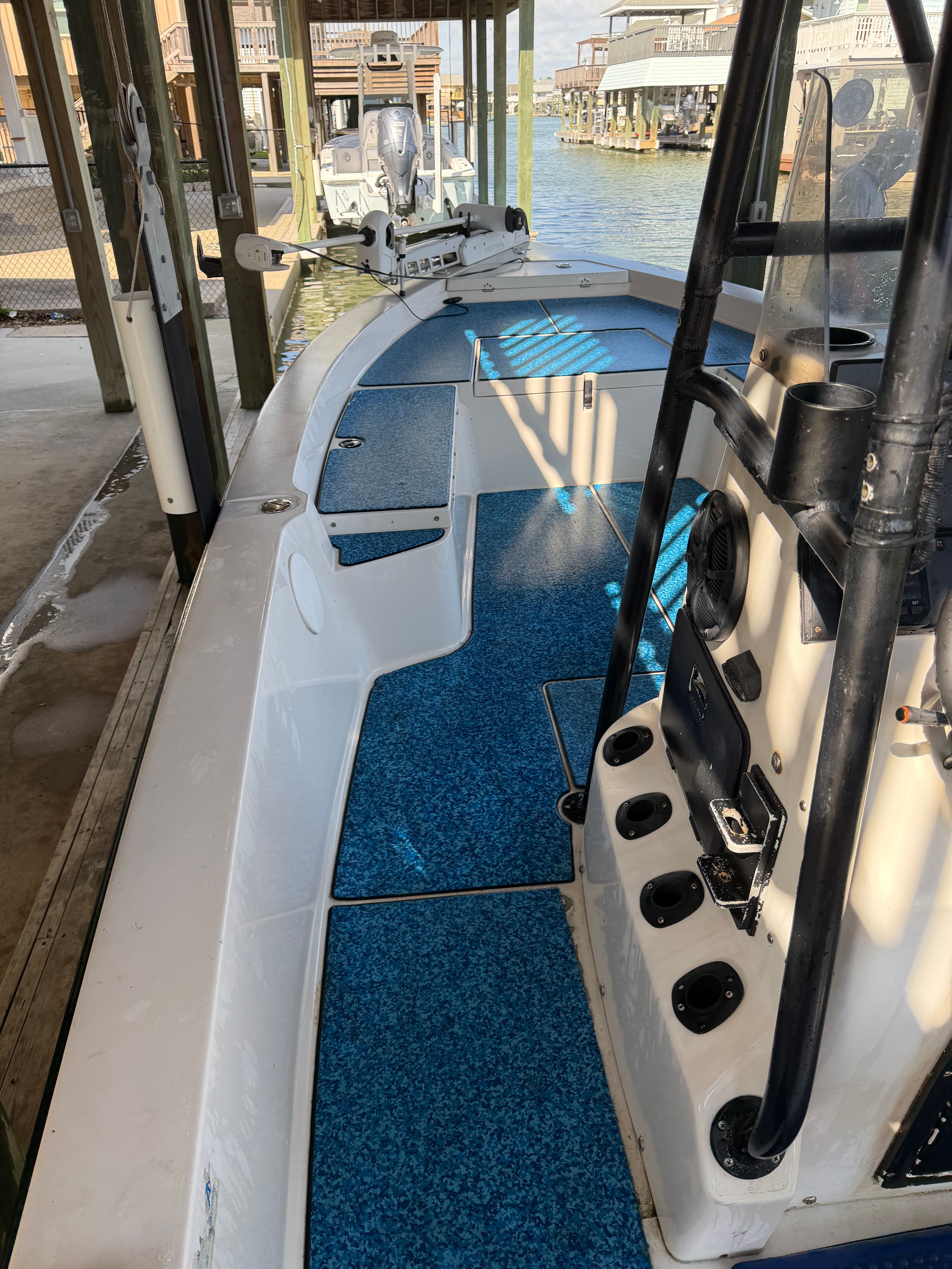 A white boat with blue flooring is docked in a covered area.