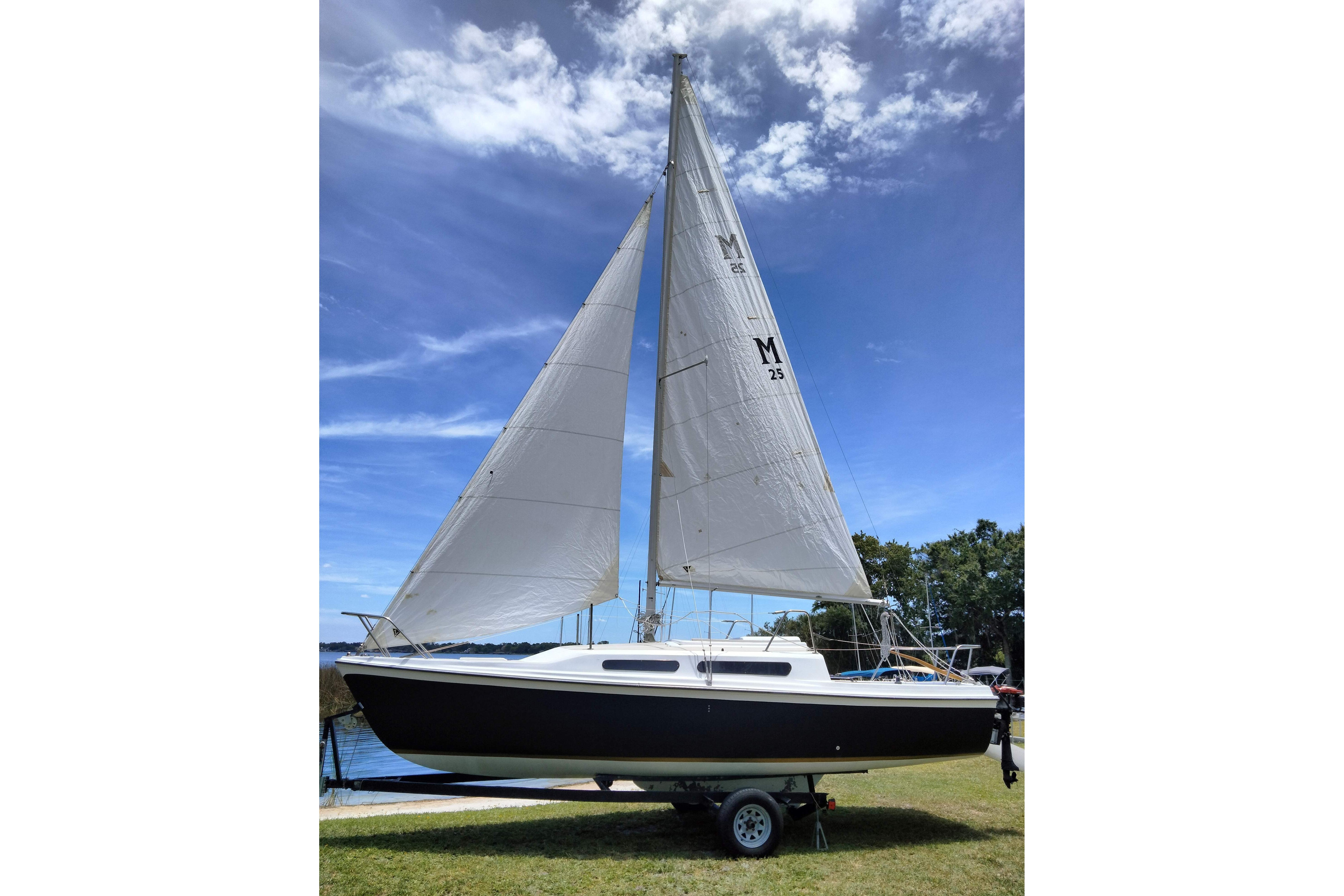 1980 MacGregor 25 sailboat on trailer, set against a clear blue sky.