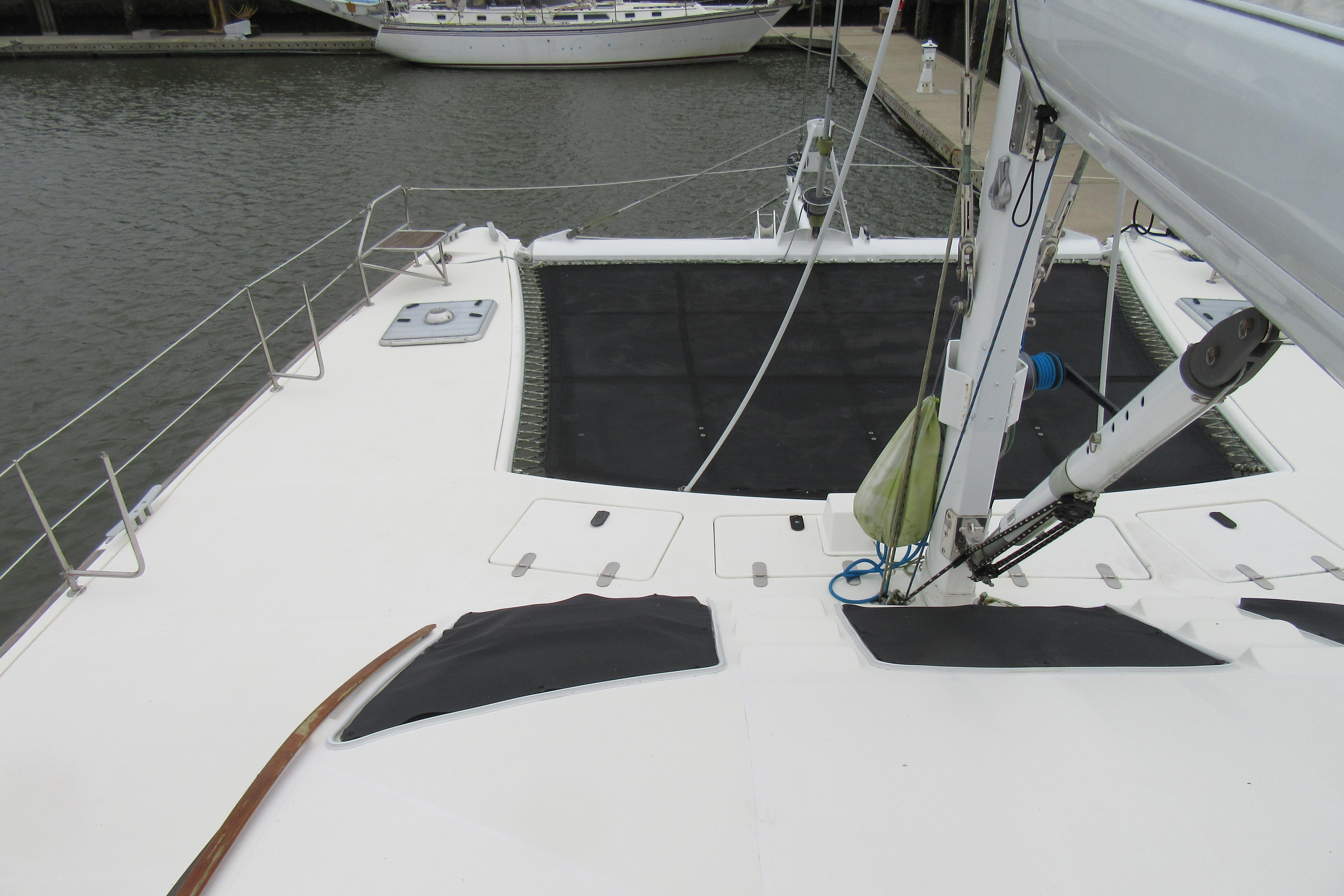 2001 Catana 471 catamaran deck view with rigging and netting, docked in marina.