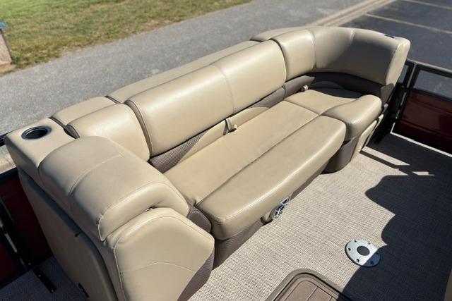 Beige seating on 2025 Regency 250 DL3 pontoon boat, featuring cup holder and carpeted flooring.