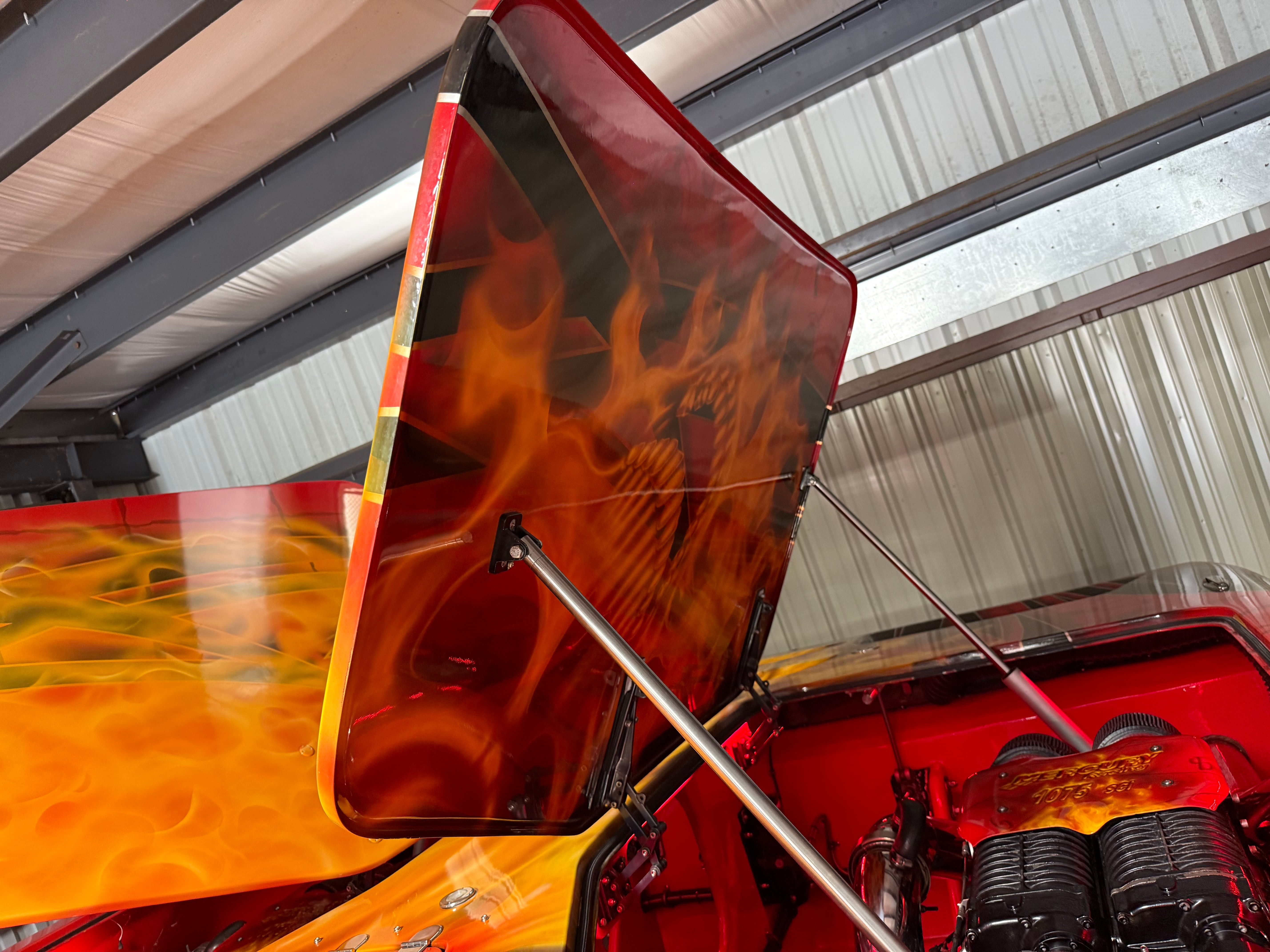A boat with a striking flame design on the engine cover, situated in a warehouse.