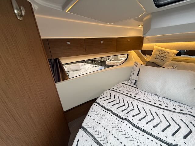 Interior of a 2021 Jeanneau NC 1095 with cozy bed and wood paneling.