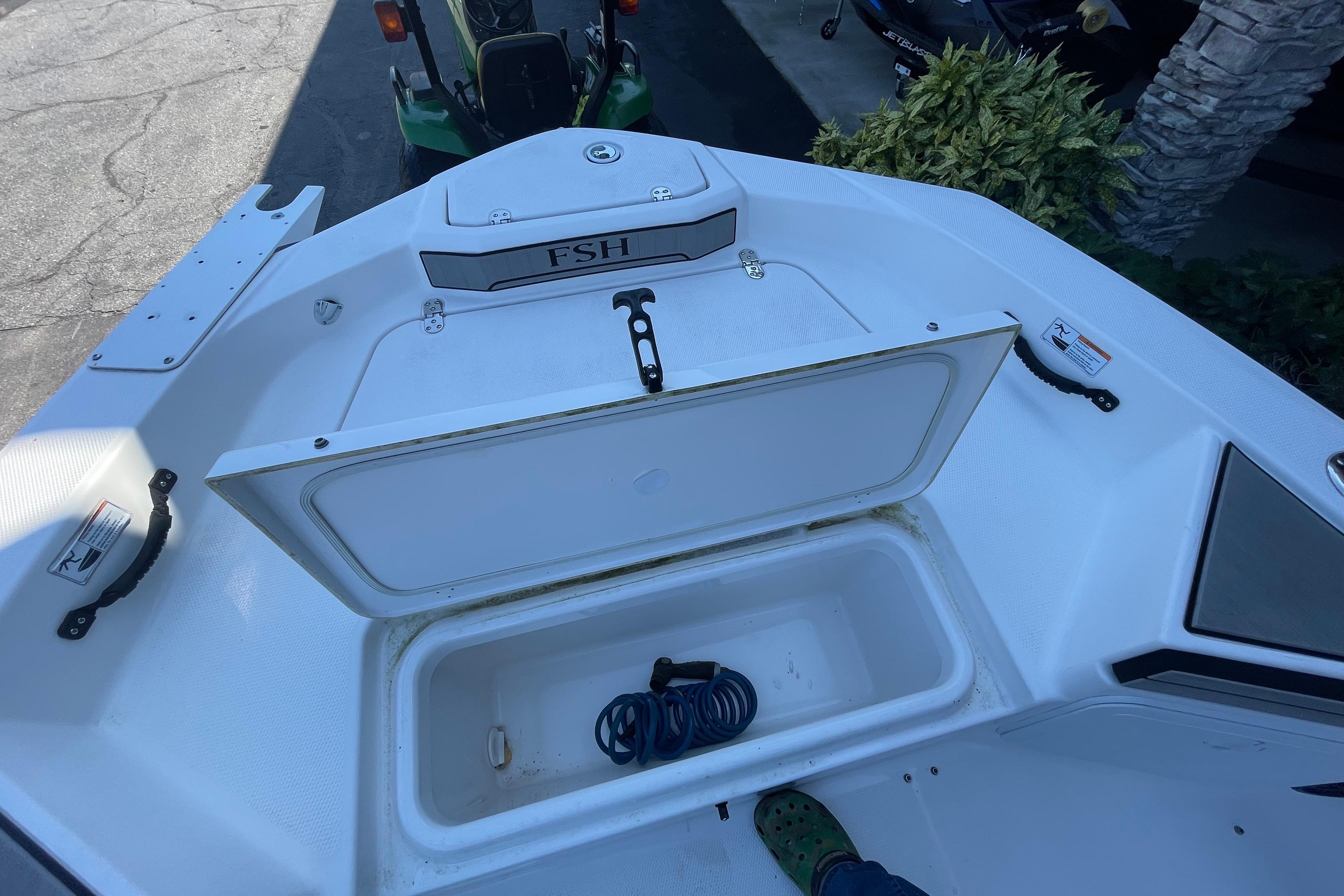 2021 Yamaha Boats 195 FSH Sport storage compartment with open lid and coiled rope inside.