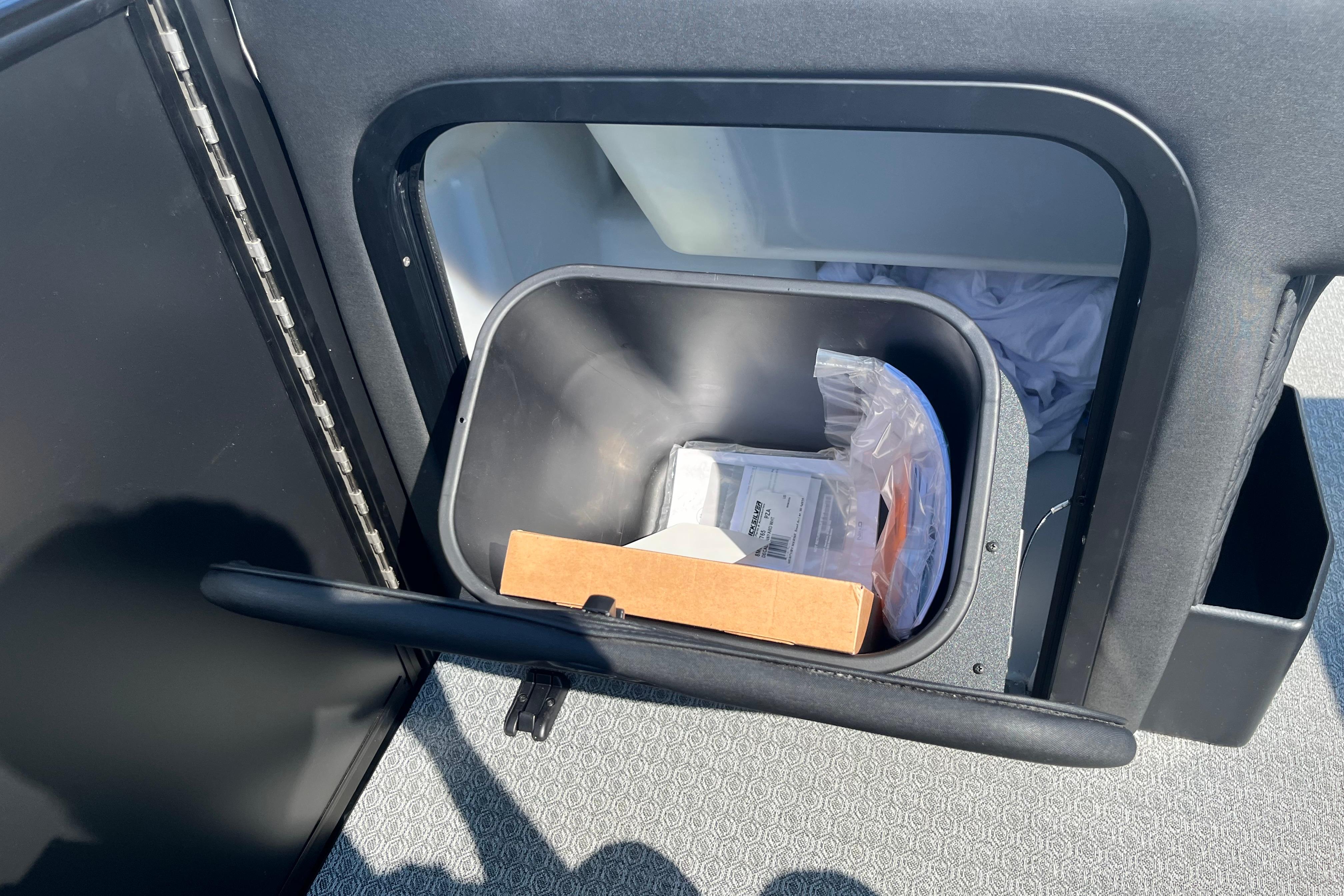 Trash bin inside Evotti 725CS, 2026 model, with various items, open compartment view.