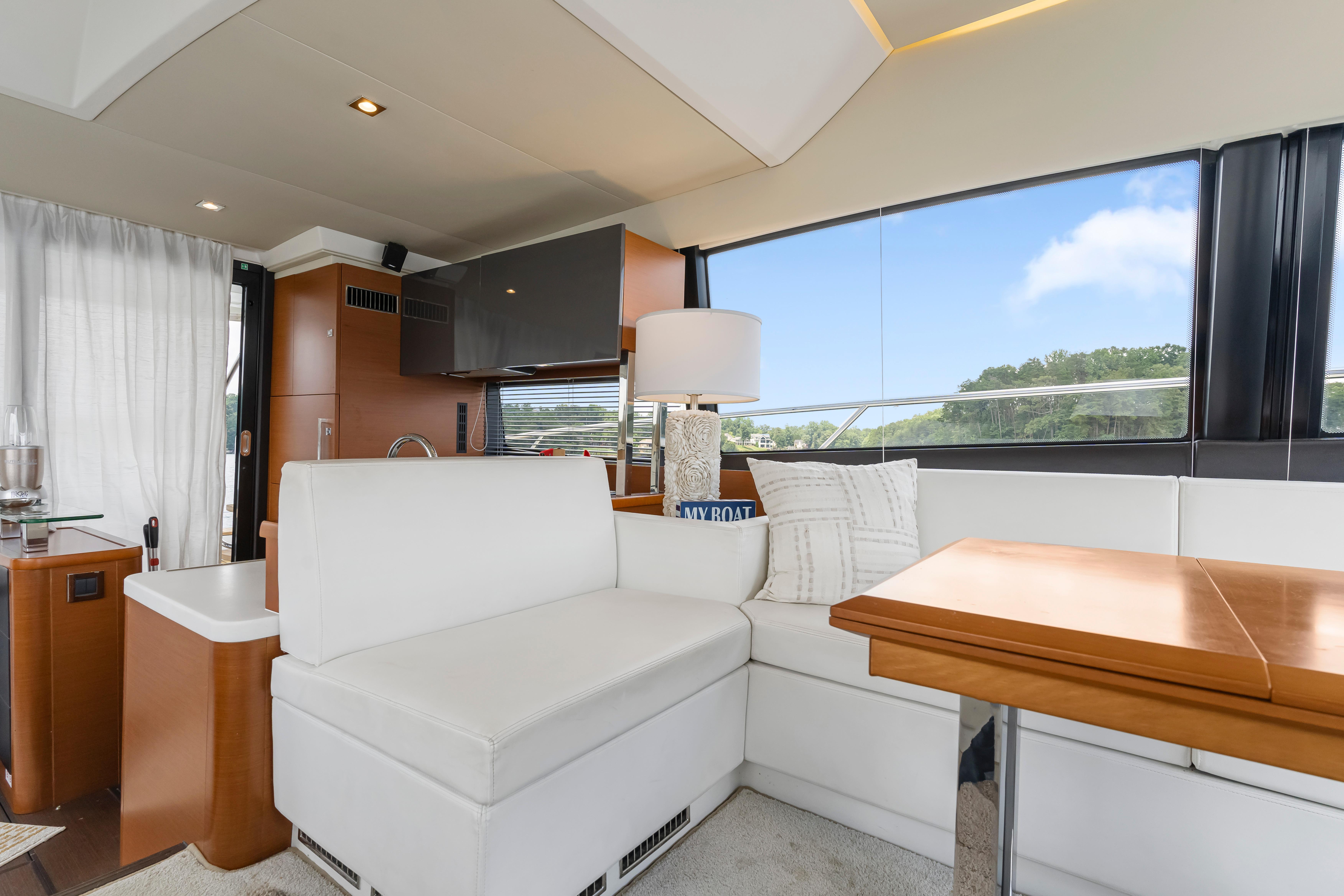 Luxurious interior of a 2017 Prestige 500 yacht with white seating and wooden table.
