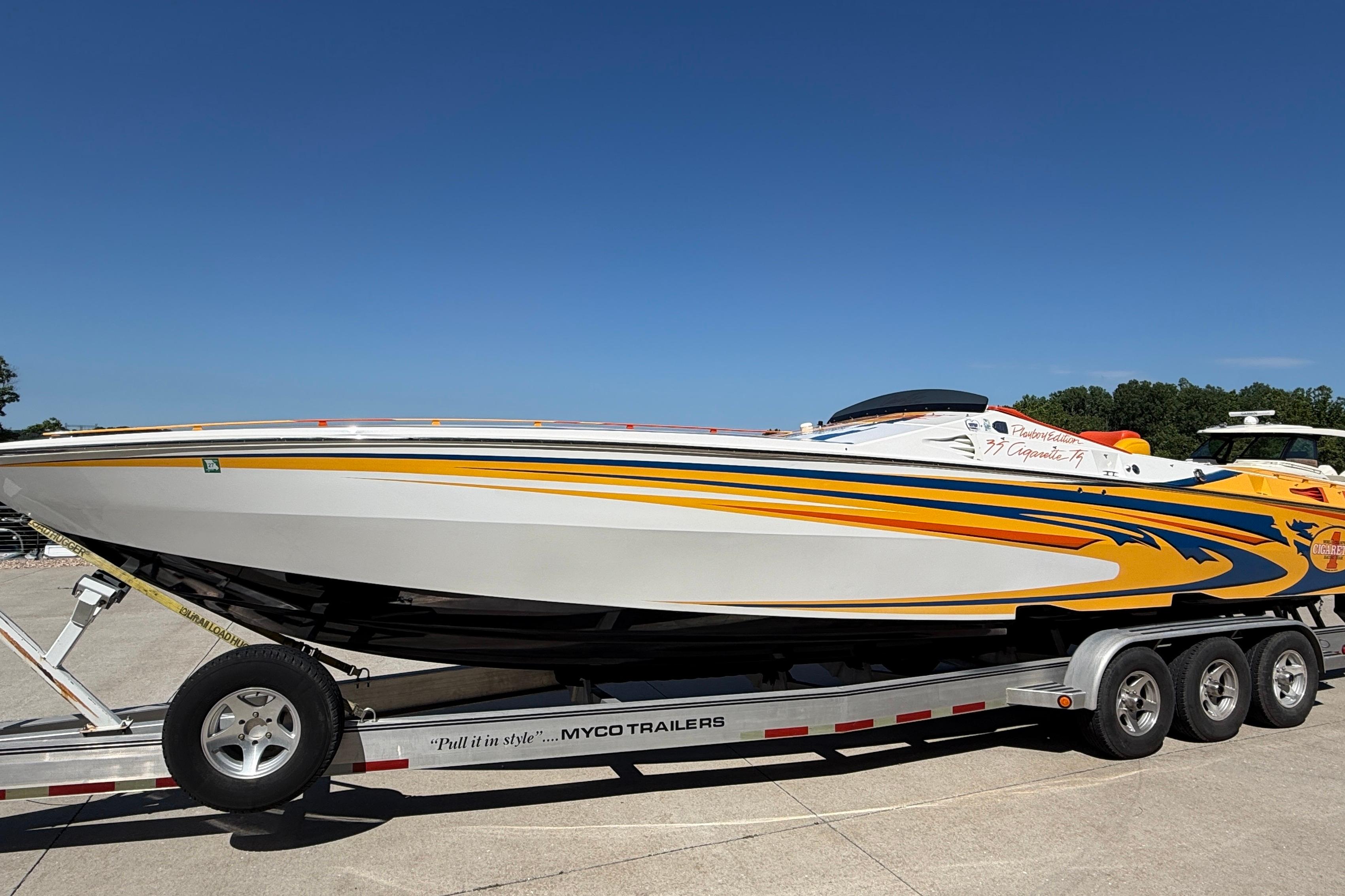 2002 Cigarette 35' Cafe Racer boat on trailer, vibrant yellow and blue design.