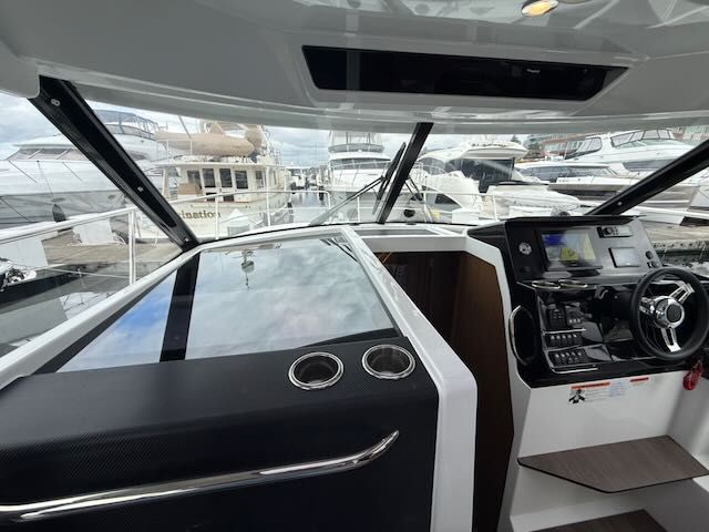 Interior view of a modern boat helm with steering wheel and instruments.