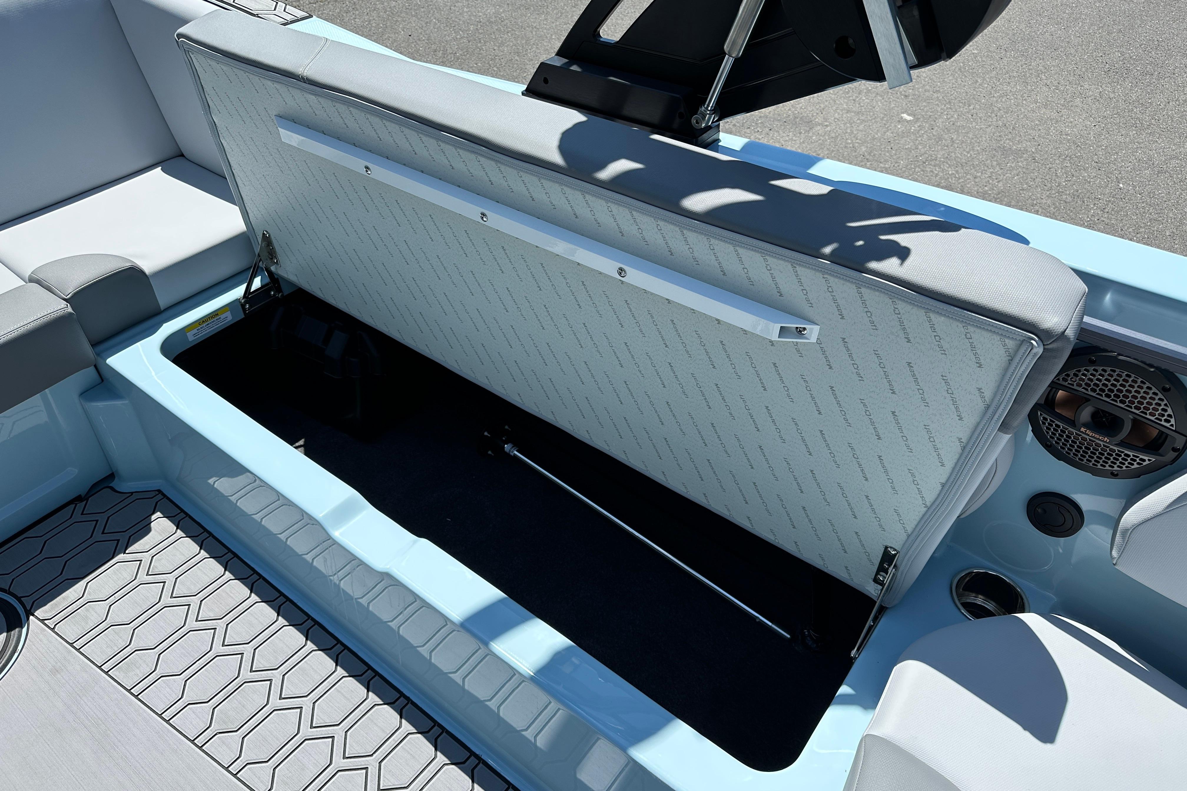 2023 MasterCraft NXT23 boat interior storage compartment with open seat and speaker.
