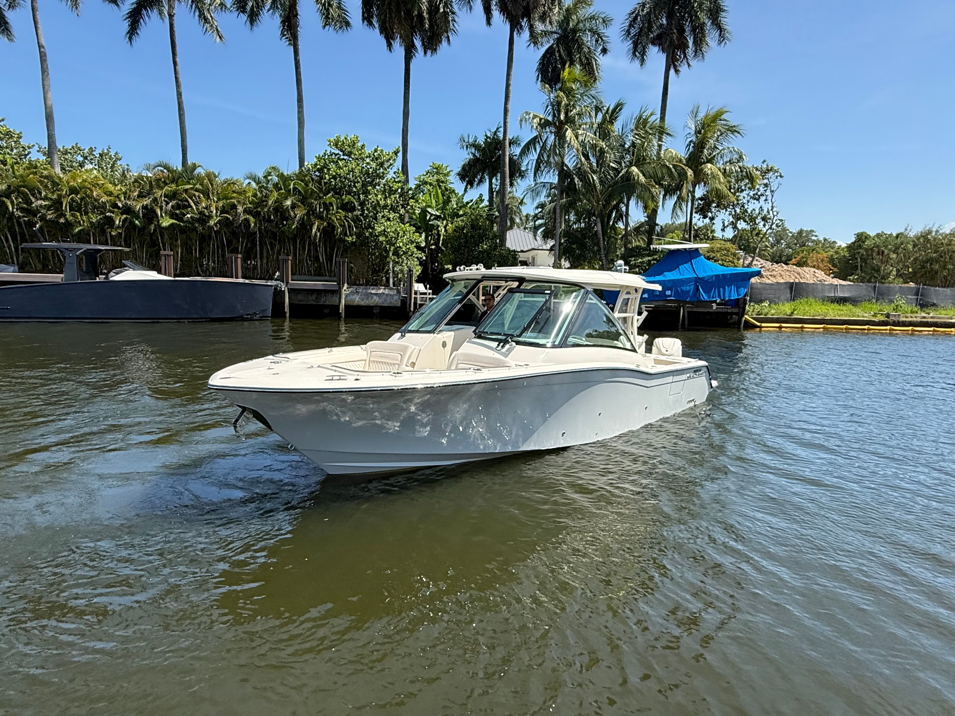 2027 Grady-White Freedom 325 on calm water, surrounded by palm trees.