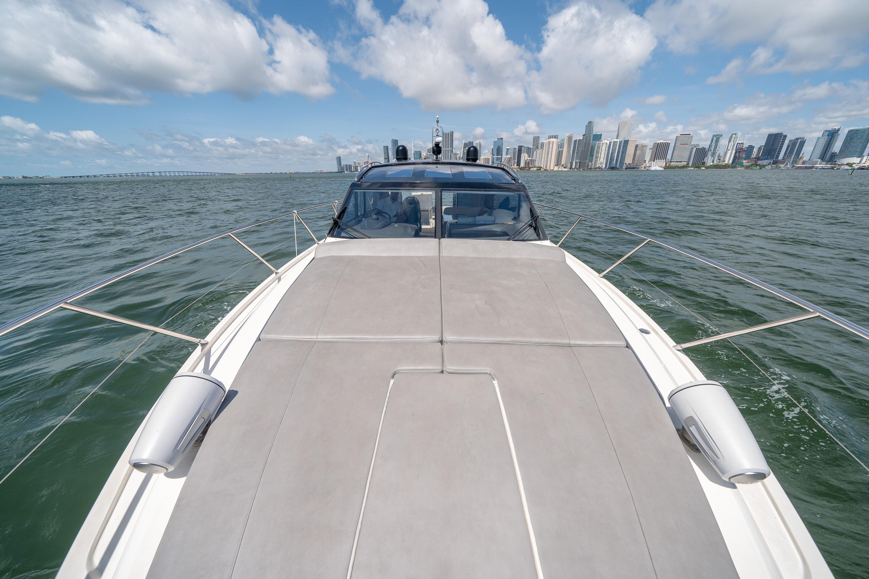 2012 Princess V52 yacht cruising on open water with city skyline in background.