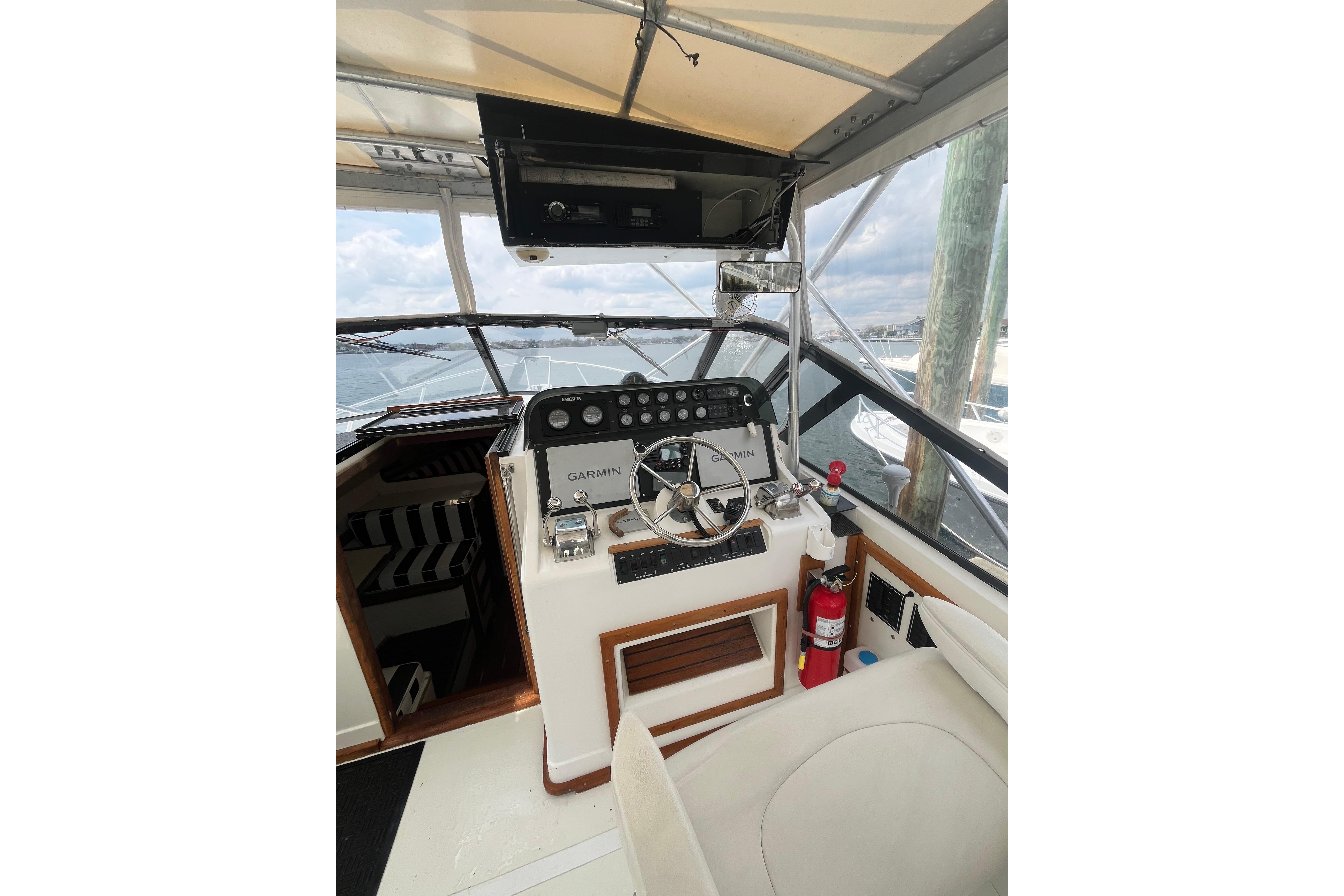 1989 Blackfin 31 Combi boat cockpit with steering wheel, Garmin controls, and fire extinguisher.