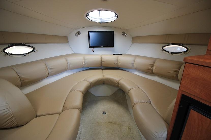 2005 Larson Cabrio 310 interior with beige seating and wall-mounted TV.