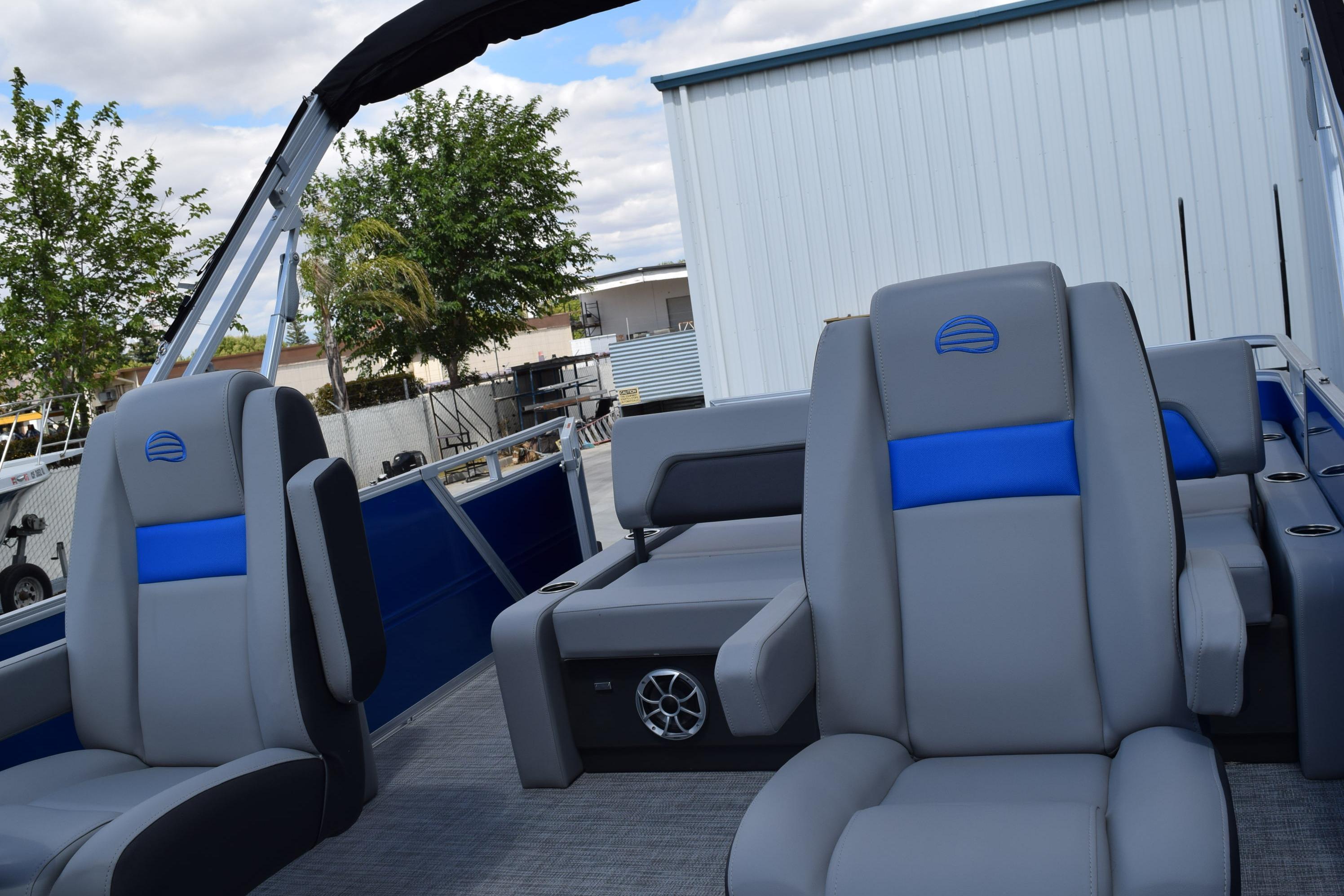 2026 Sun Tracker Party Barge 22 RF DLX with gray and blue seating, outdoor setting.