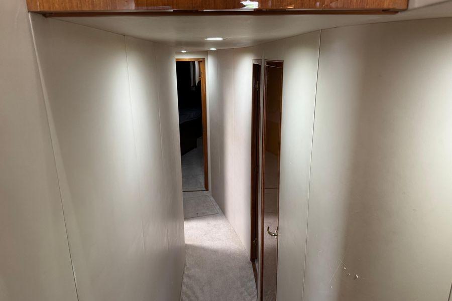 Interior hallway of 2002 Viking 61 Enclosed Bridge yacht, featuring carpeted flooring and wooden accents.
