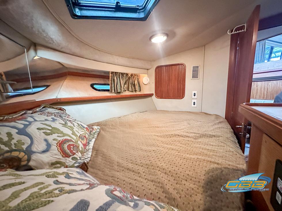 Cozy bedroom in 1989 Carver 3807 Aft Cabin yacht with skylight and patterned pillows.