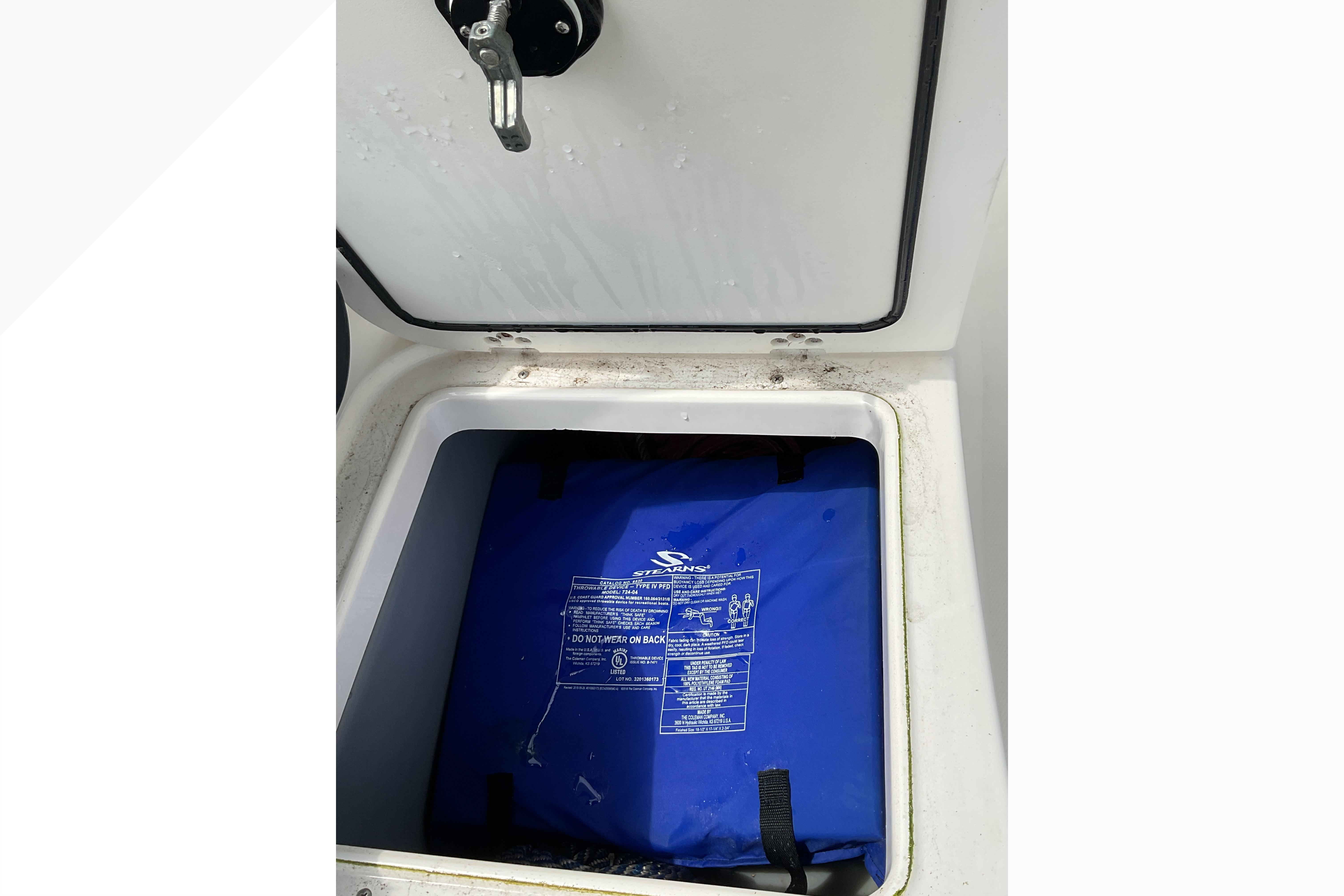 Open storage compartment on 2012 Wellcraft 232 Coastal boat with blue life jacket inside.