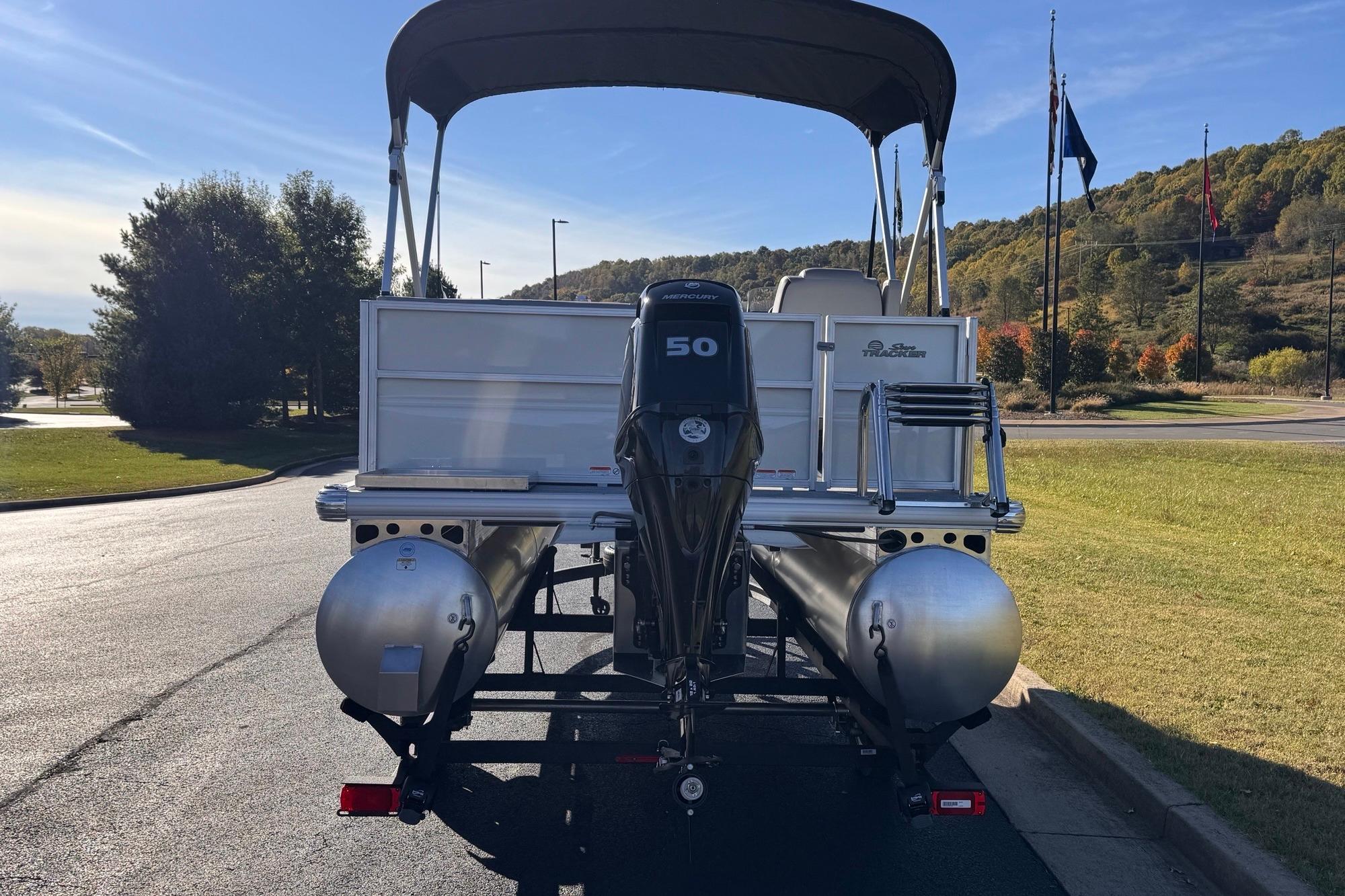 2026 Sun Tracker Party Barge 16 DLX pontoon boat with outboard motor, parked outdoors.