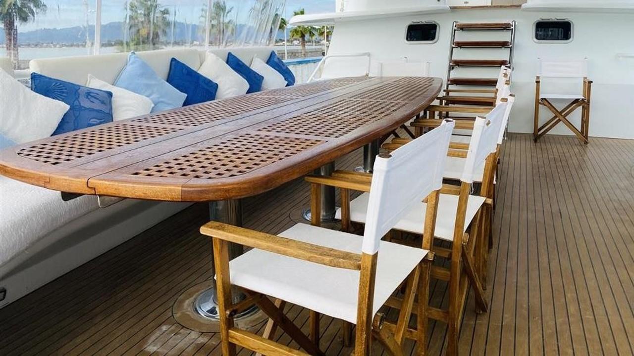 Luxurious deck of 2005 Explorer Motor Yachts 28M with wooden table and chairs.