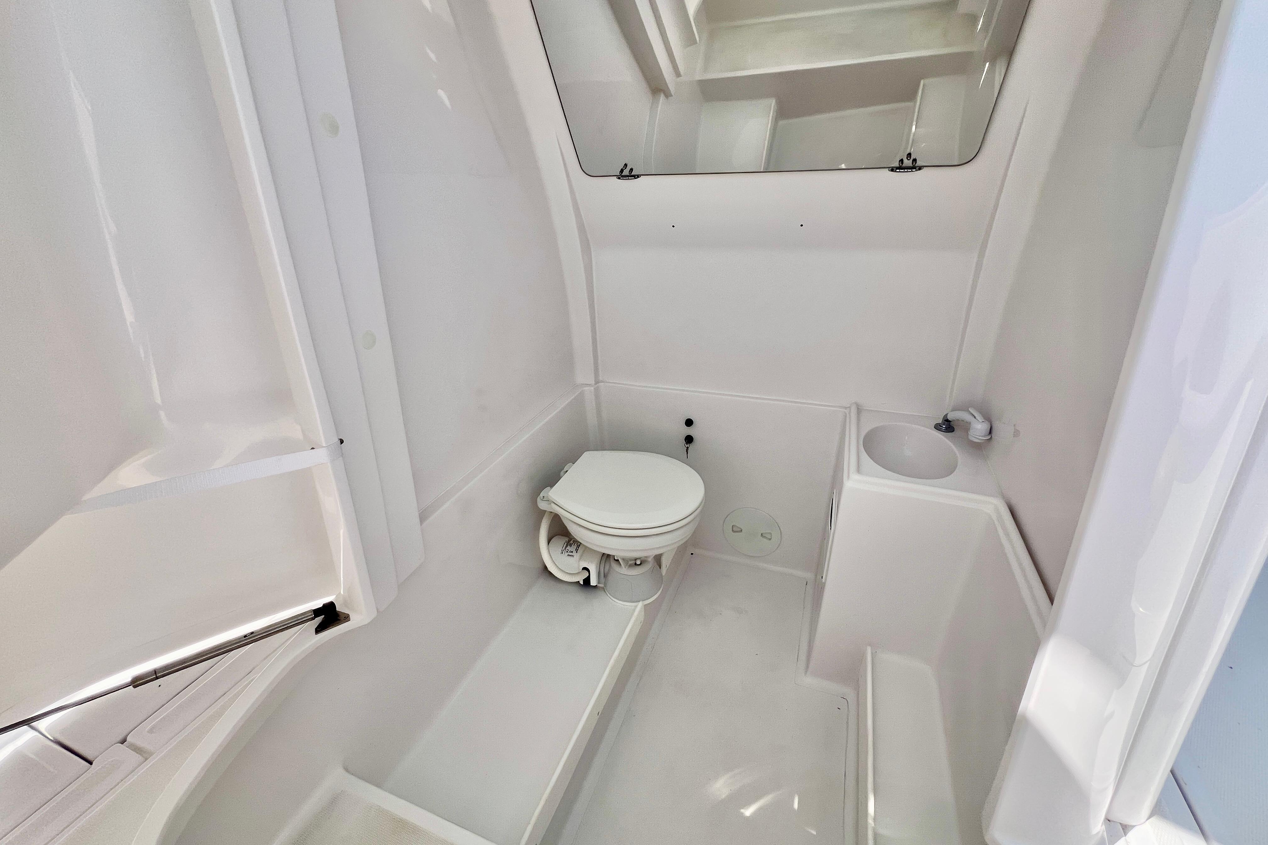 2026 Stamas 31T Aventura boat bathroom with toilet and sink, featuring sleek white design.