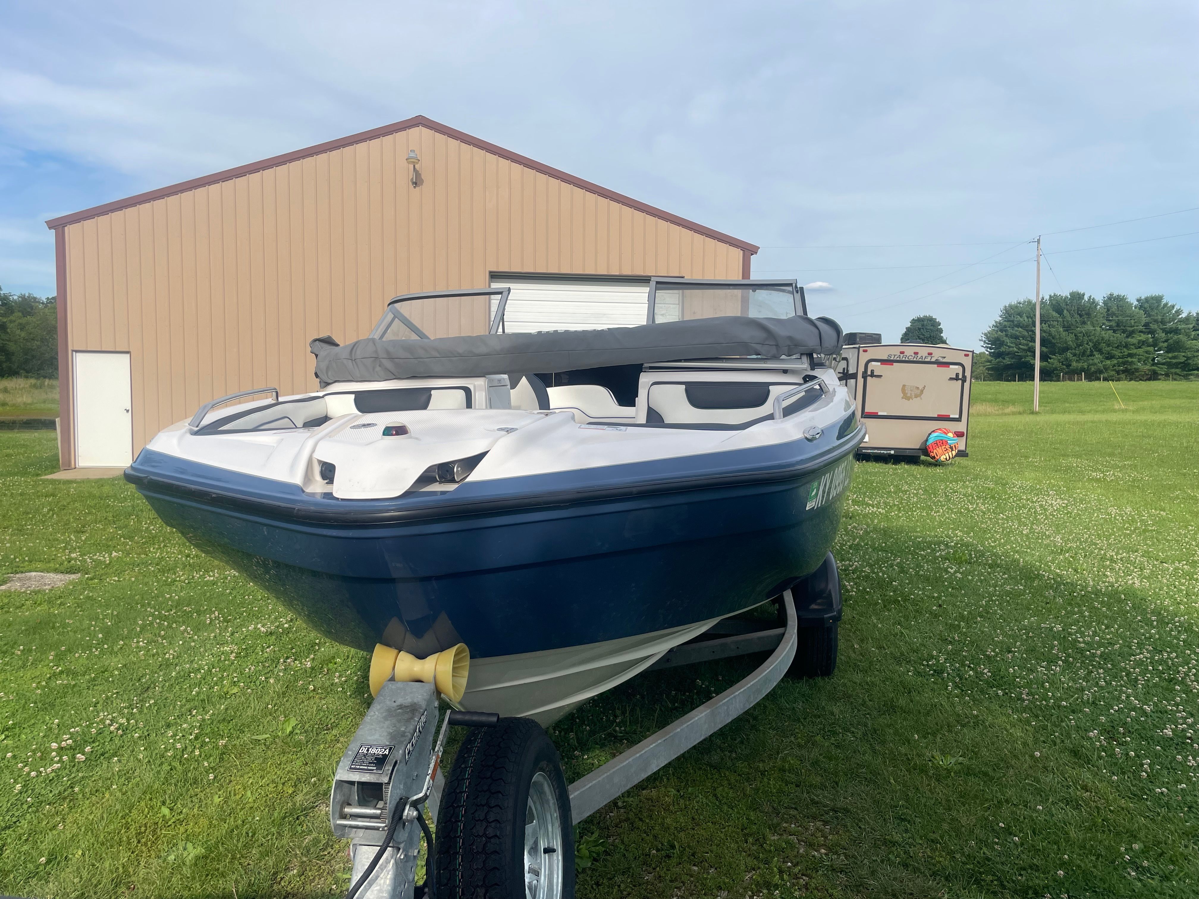 A 2019 Yamaha SX210 boat on a trailer in front of a building on a grassy field.