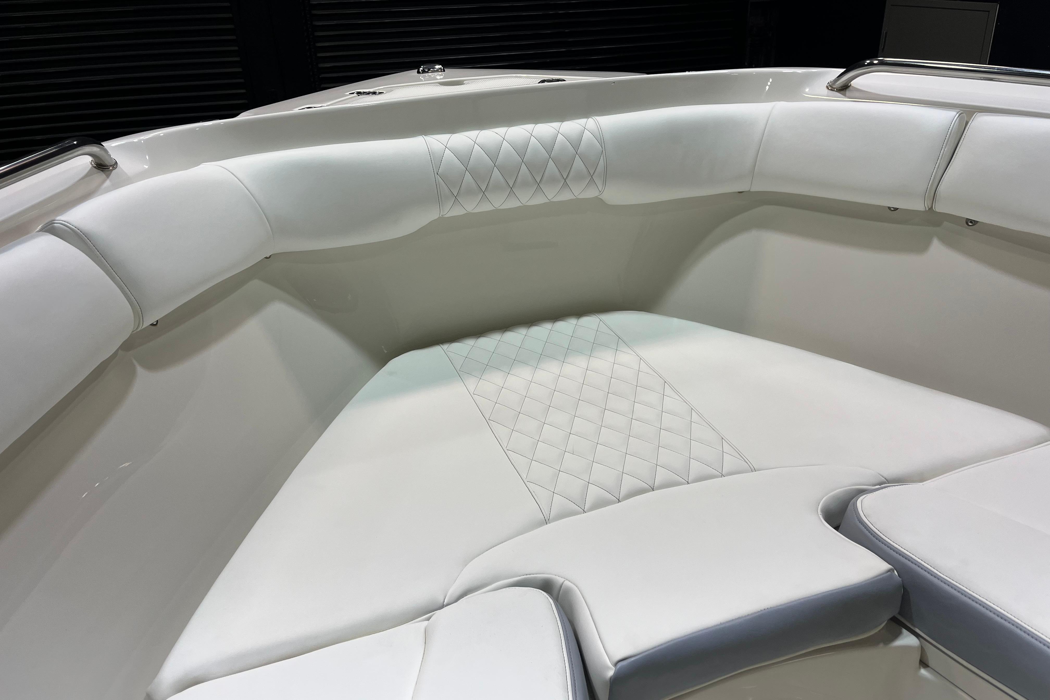 Luxurious white seating in 2022 Sailfish 242 CC boat, featuring diamond-pattern upholstery.