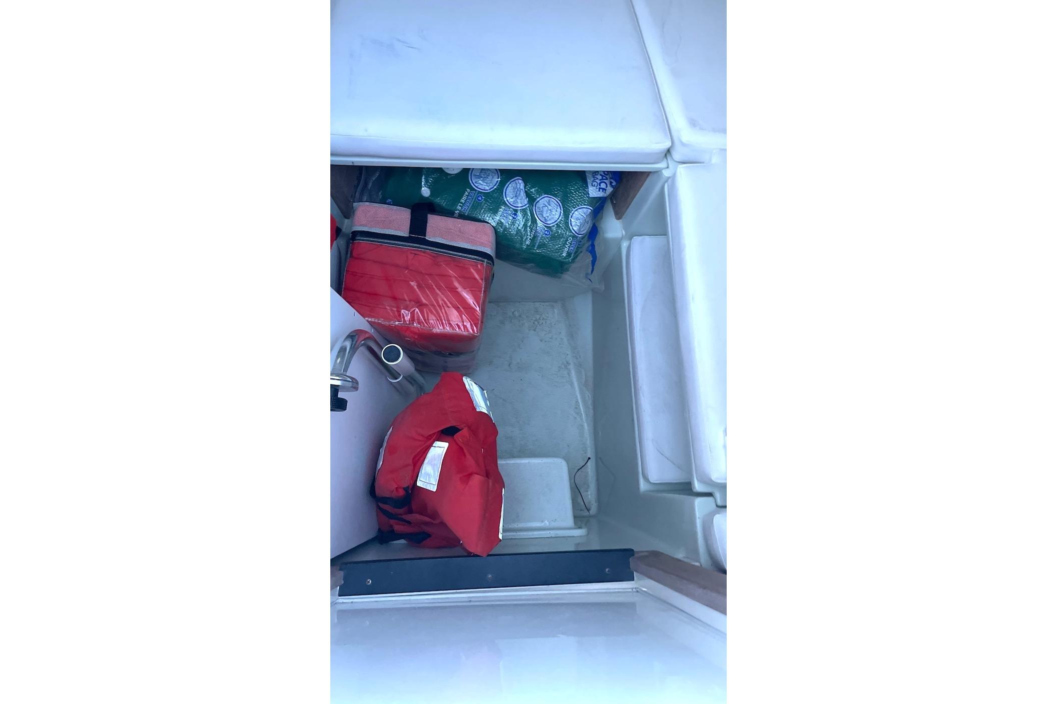 Storage compartment in a 2002 Intrepid 323 Cuddy boat with life jackets and supplies.