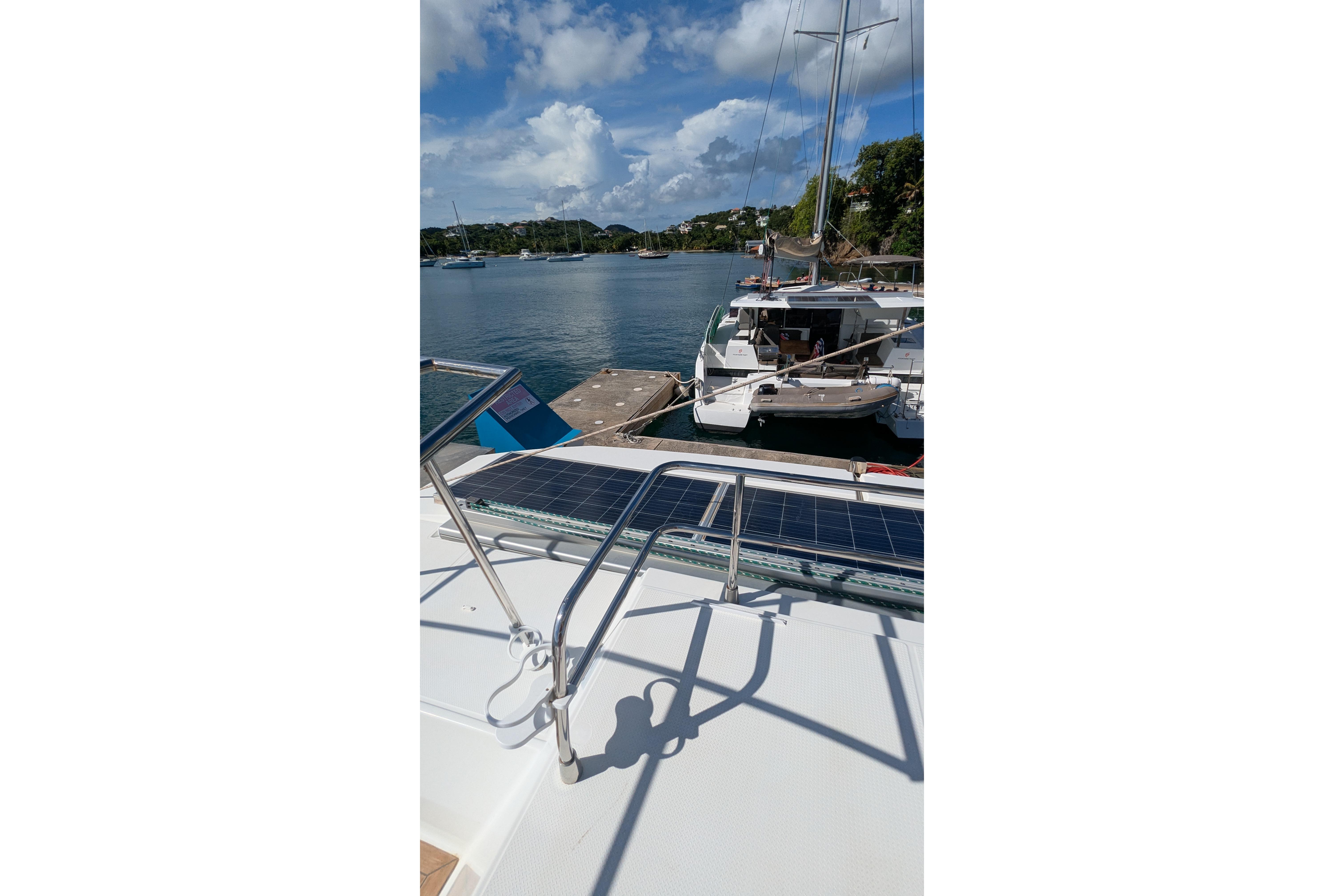 2020 Fountaine Pajot Saona 47 catamaran docked, featuring solar panels and scenic waterfront view.
