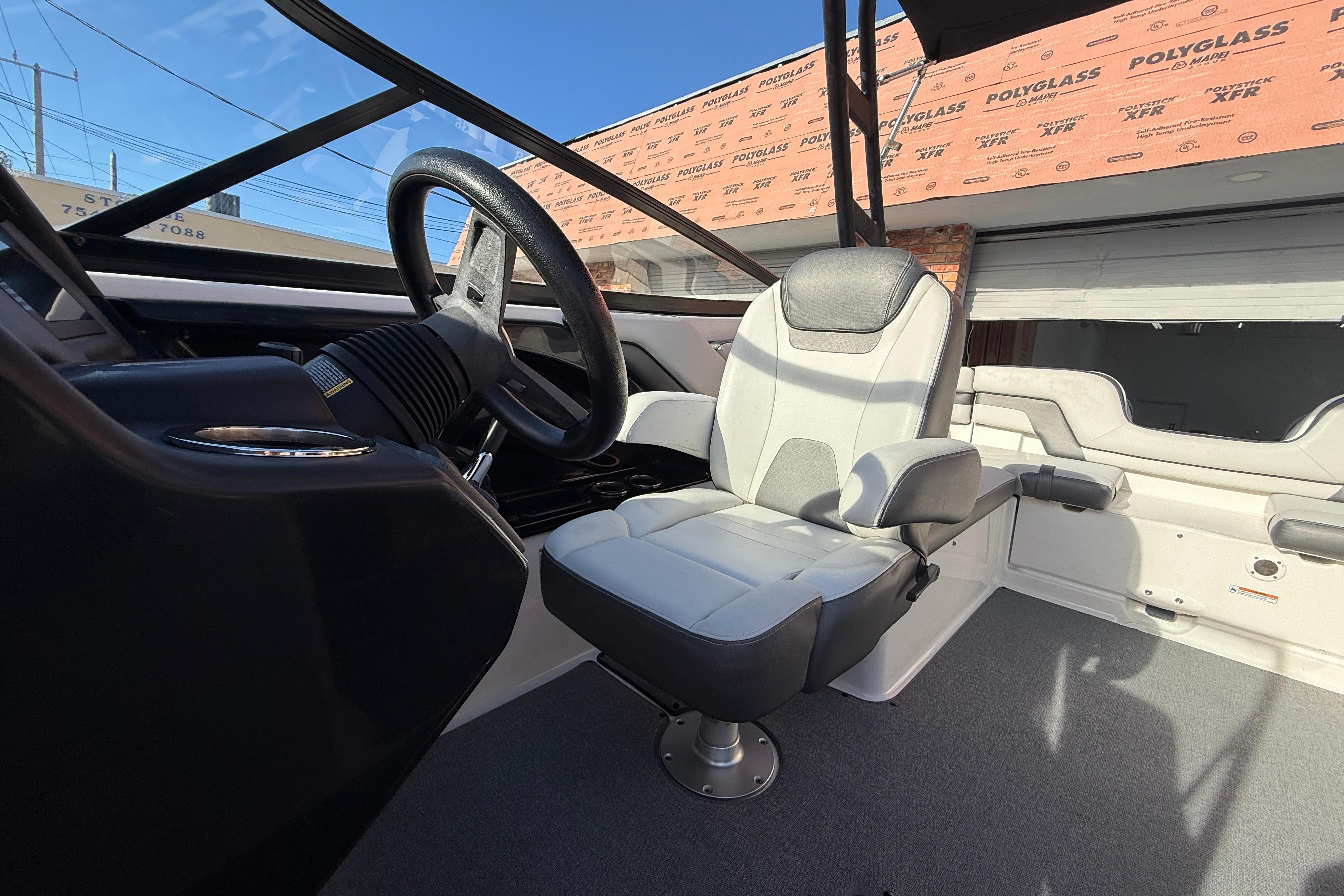 Interior of a 2020 Yamaha Boats AR230, featuring a sleek captain's chair and steering wheel.