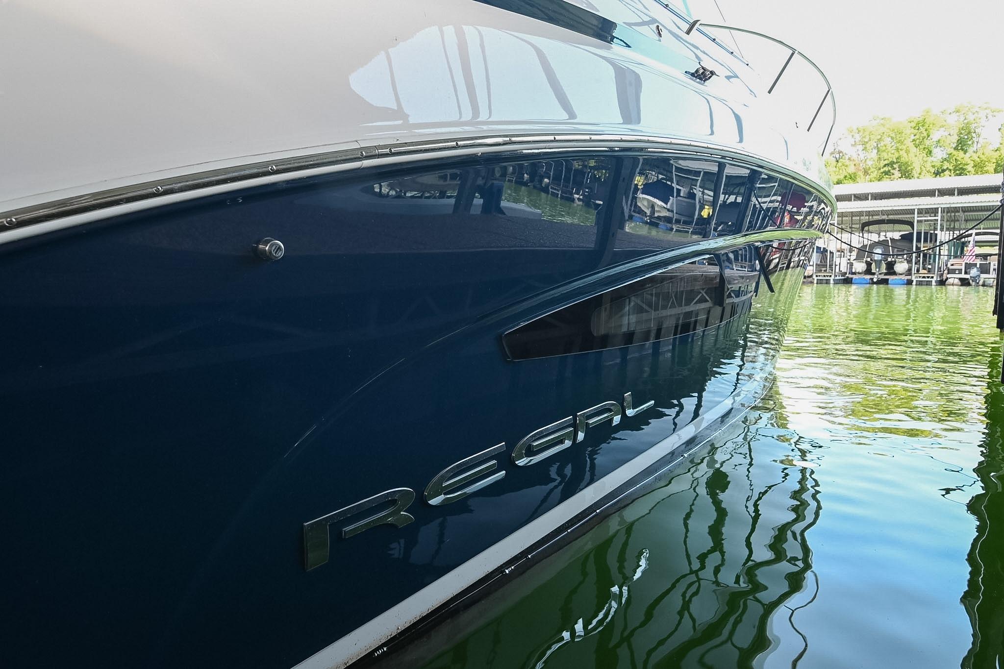 2021 Regal 33 Express yacht docked on calm water, reflecting marina surroundings.