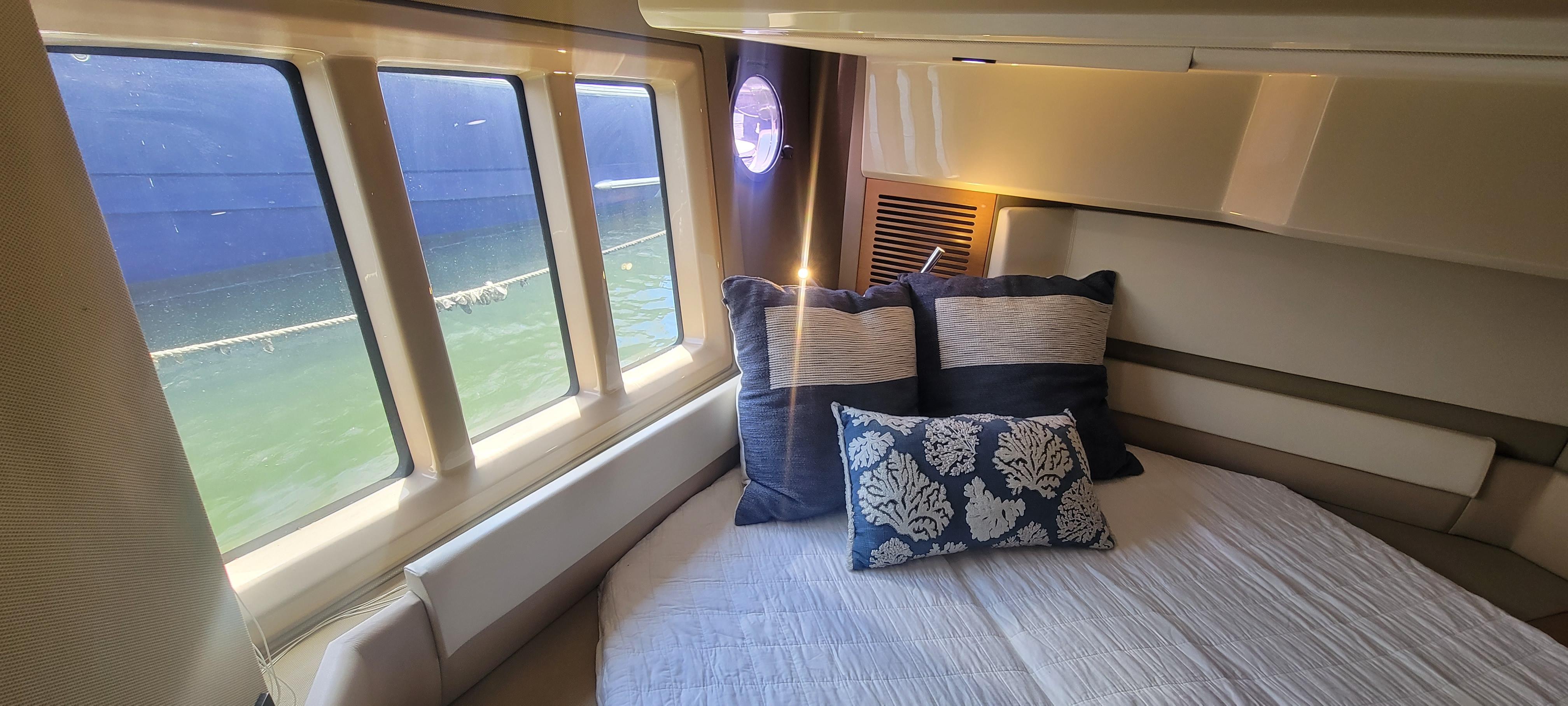 Luxurious bedroom interior of 2013 Azimut 45 Flybridge yacht with large windows and plush pillows.