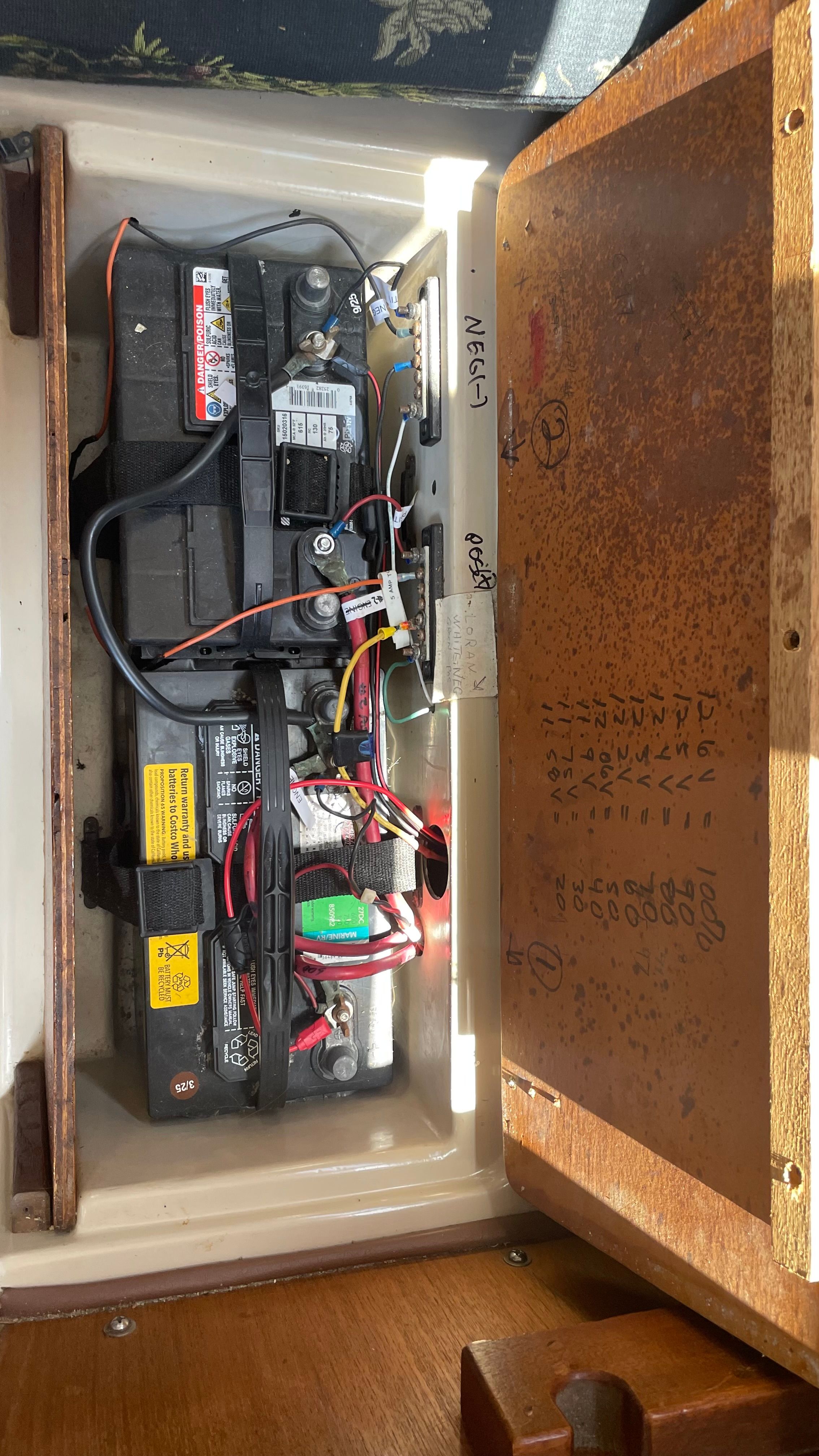 Battery compartment of a 1980 Newport 30 boat with two batteries and wiring.
