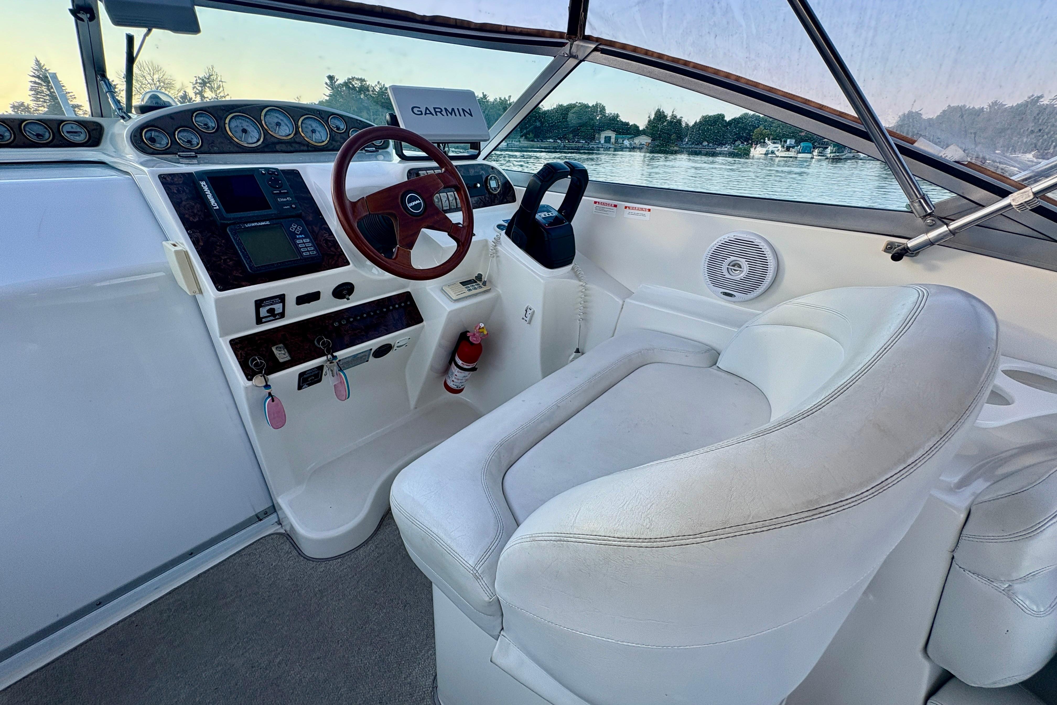 1998 Doral 300SC boat cockpit with steering wheel, Garmin navigation, and white seating.