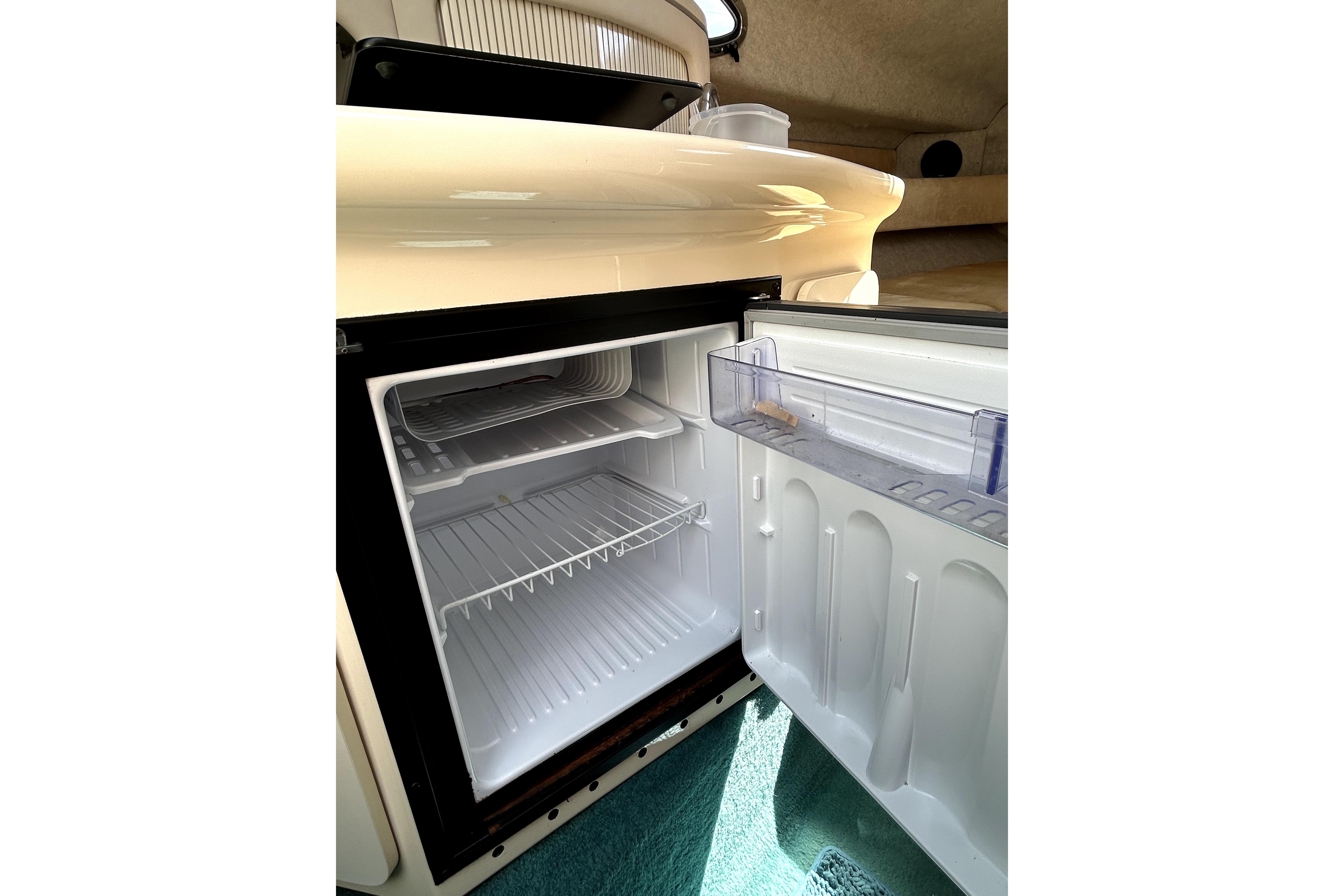 Open refrigerator inside 1995 Sea Ray 250 Sundancer boat cabin.