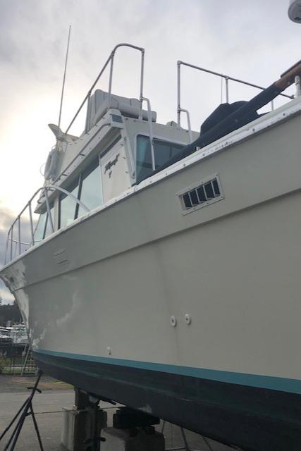 1978 Tollycraft 34 Sedan boat on dry dock, side view, overcast sky.