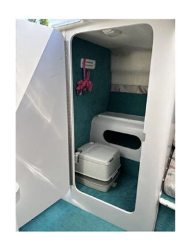 Interior of a 1993 Chris-Craft 238 Cuddy Concept with a toilet and blue carpet.