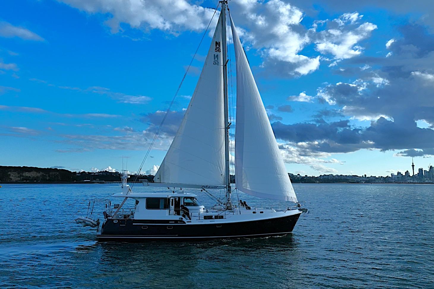 2009 Nordhavn 56 Motorsailer sailing on a calm sea under a vibrant blue sky.