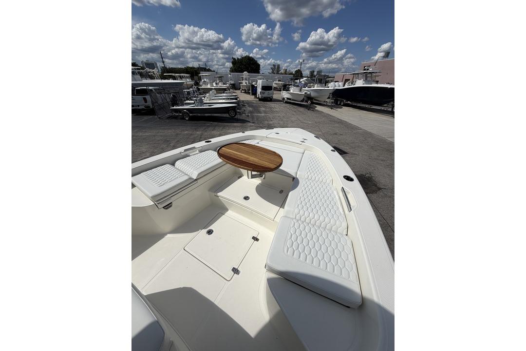 2026 Pathfinder 2800 Hybrid boat with white seating and wooden table under a cloudy sky.
