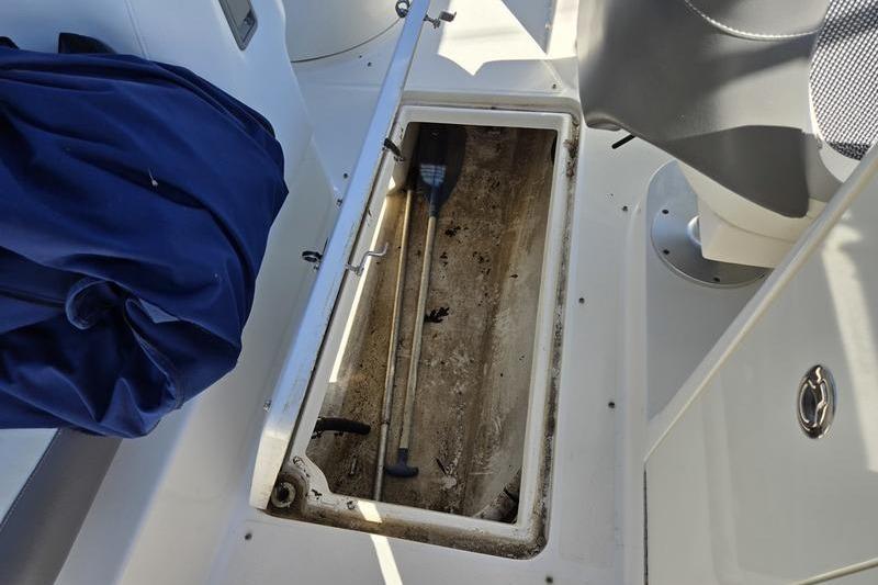 Open storage compartment on a 2011 Sea Ray 300 Sundeck boat, containing paddles.