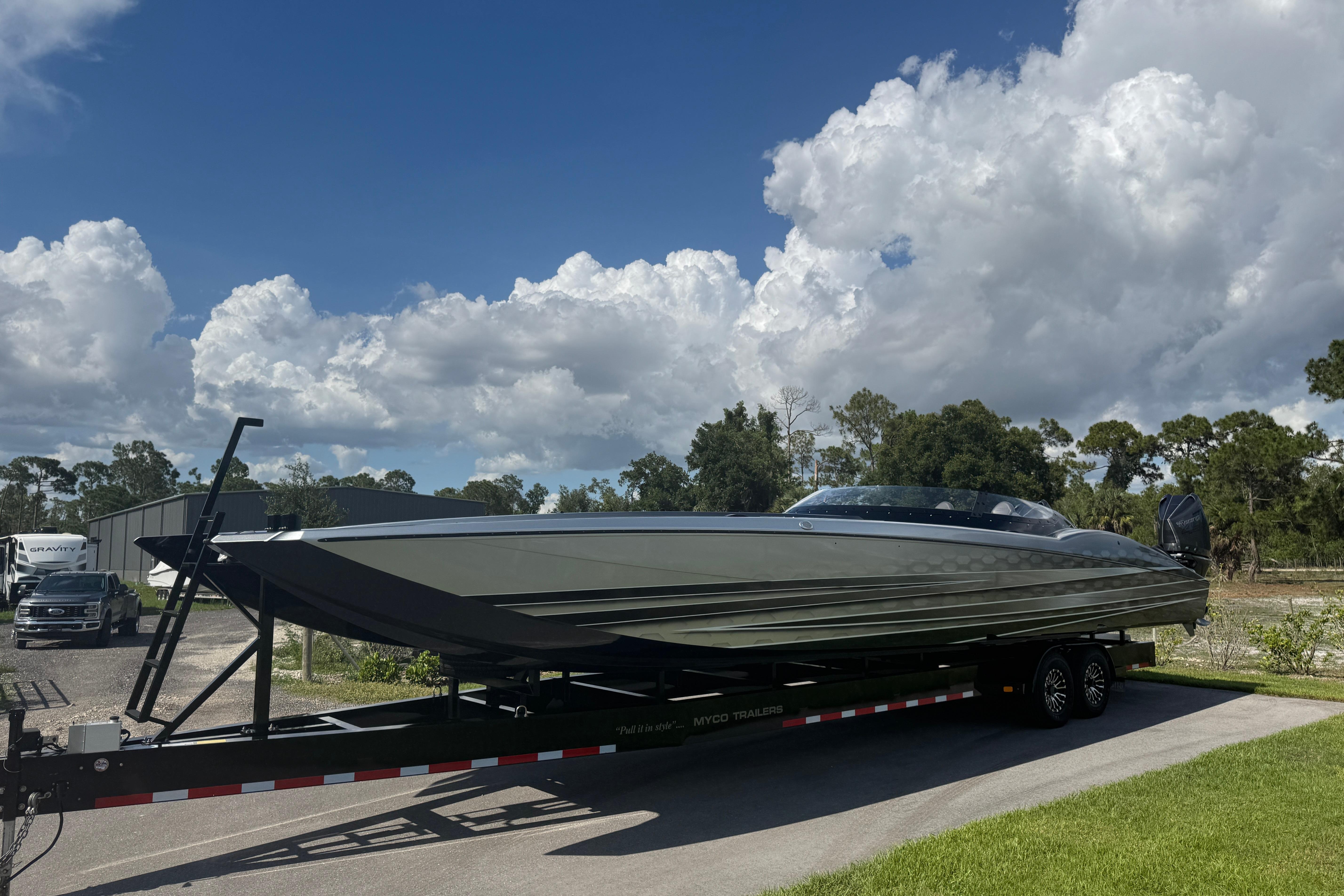 2023 MTI 390X boat on trailer under blue sky with clouds.