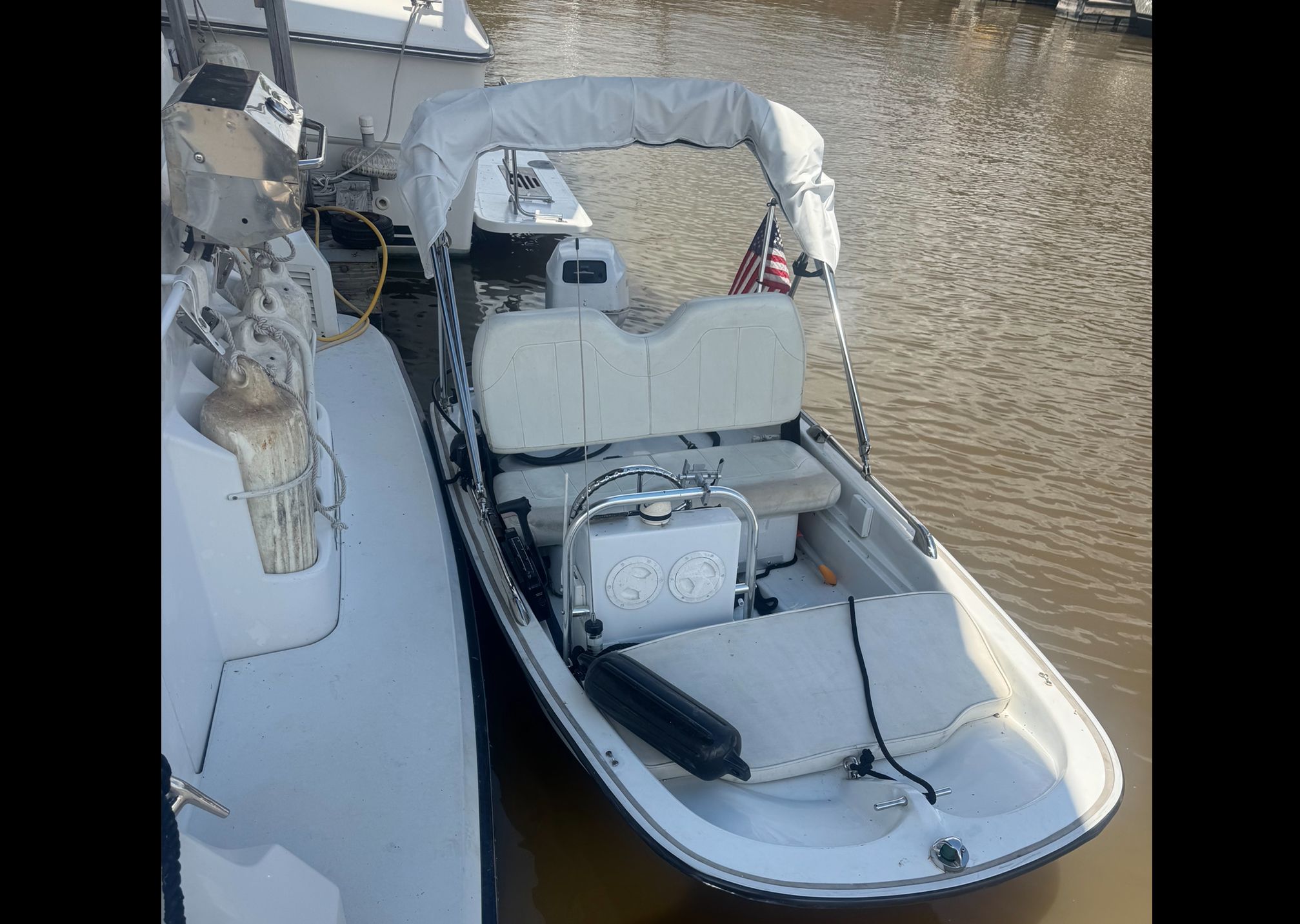A small boat with white canopy and seat cushions, docked at a pier.