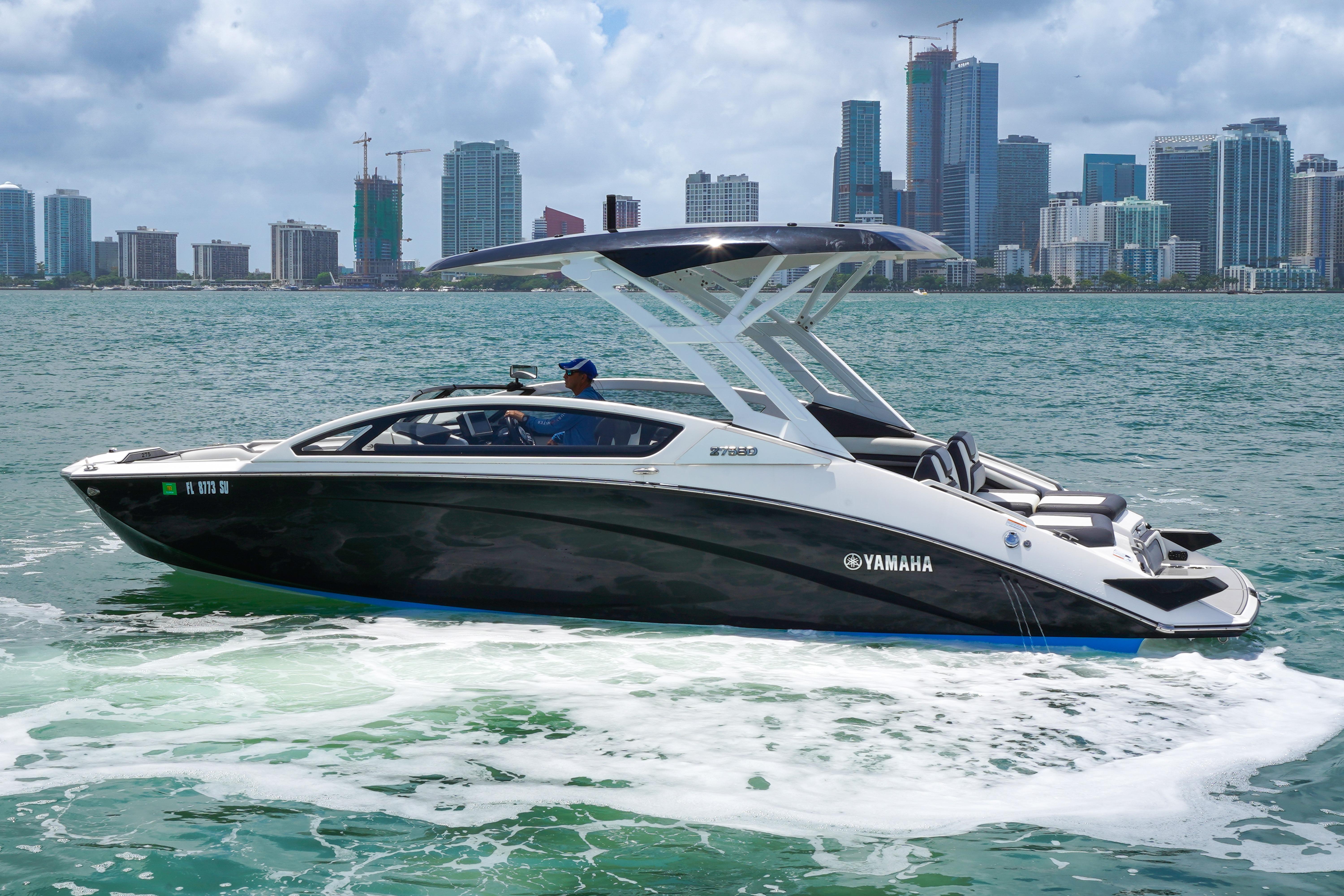 2021 Yamaha Boats 275SD cruising on water with city skyline in background.
